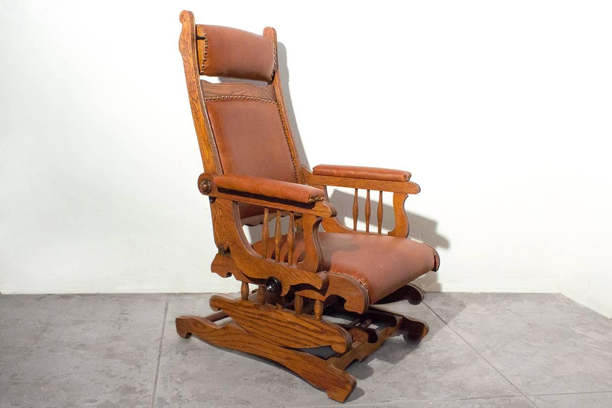 Victorian platform rocker with foot rest in excellent condition. Newly reconditioned oak frame with brown leather upholstery. Adjustable seat back, headrest and hideaway foot rest.