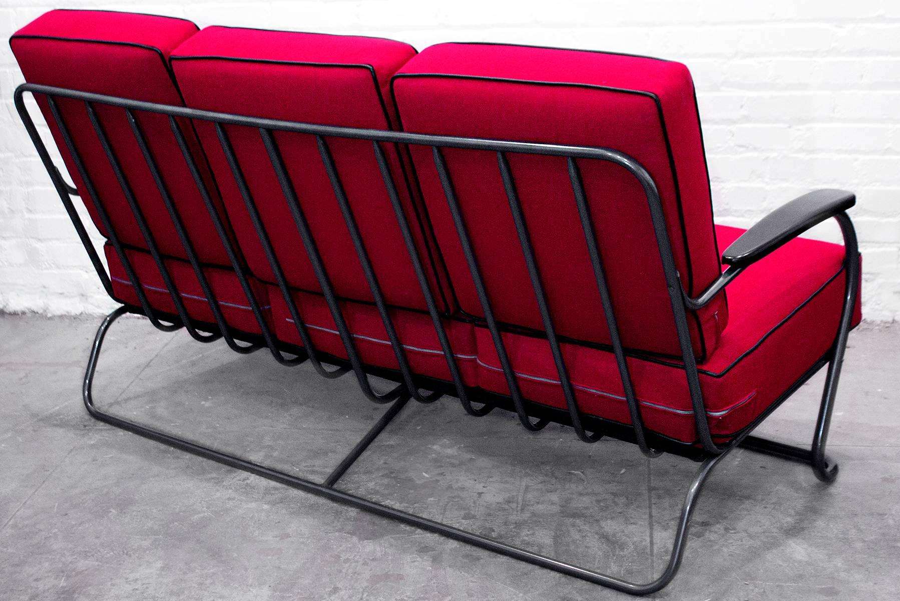 KEM Weber Classic sofa. Original chrome tube frame has been newly powder coated in a dark gray metallic. Reupholstered in crimson red micro-linen. Black Lacquer armrests. One of a kind version of this Classic.

Measures: 65" L x 35" D x
