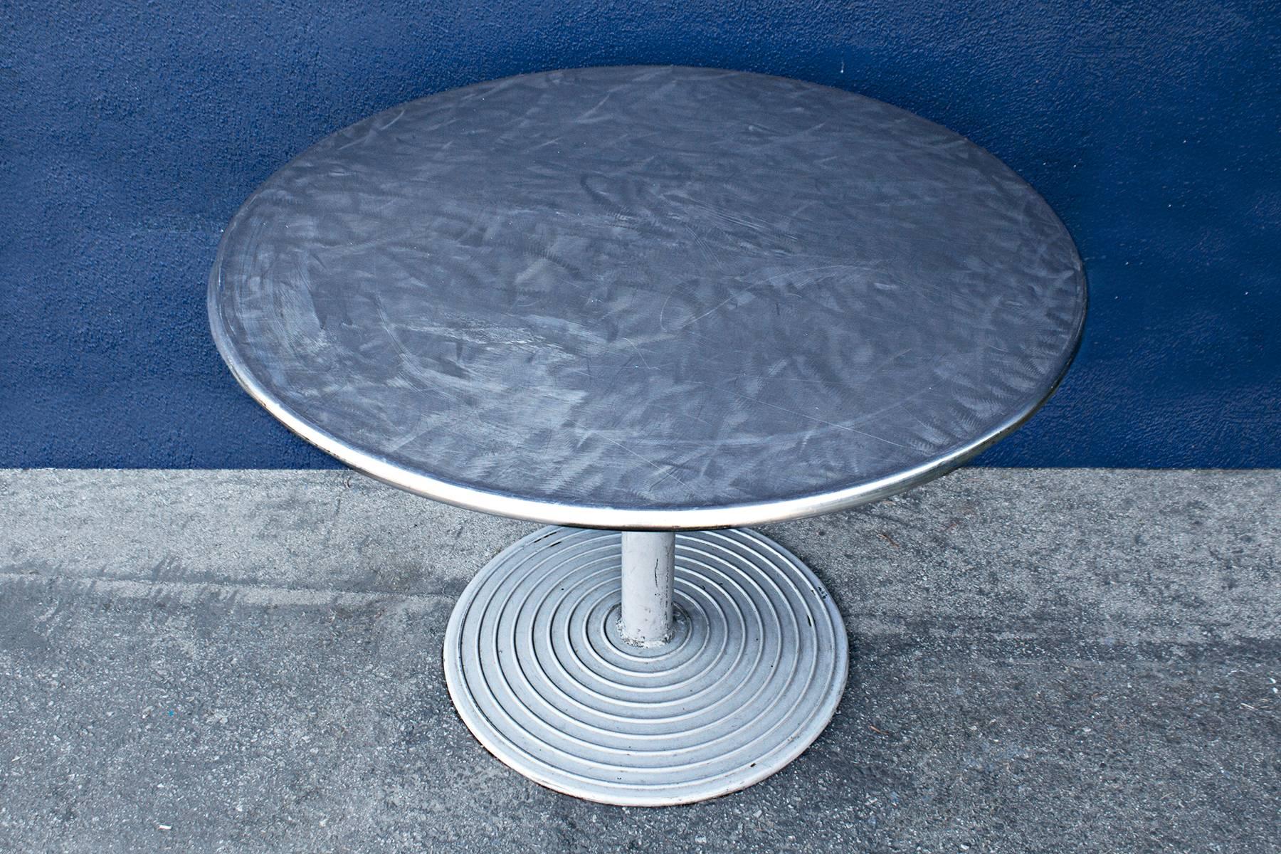Rare stainless steel cafe table mounted on Art Deco style aluminum base. Tops have been machine brusehd with circular patterns. Raised concentric circles add a great optical effect. 

 Great for back yard patios, restaurants, or hospitality. Base