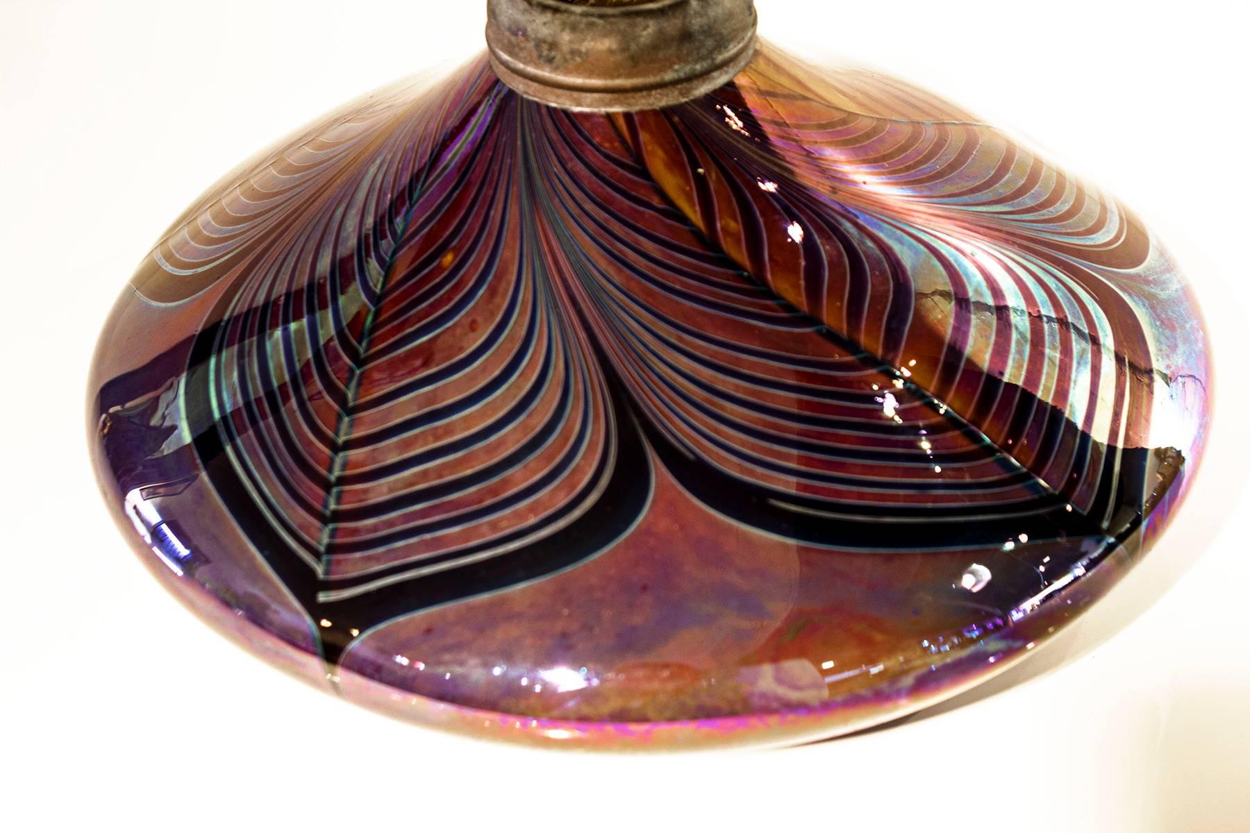 Pulled feather art glass oil lamp, with missing chimney. Highly resembles orient and flume glass. Clearly signed by David Hartman of Swallowtail in California, 1978.

Measures: 8" diameter x 4.5" height.