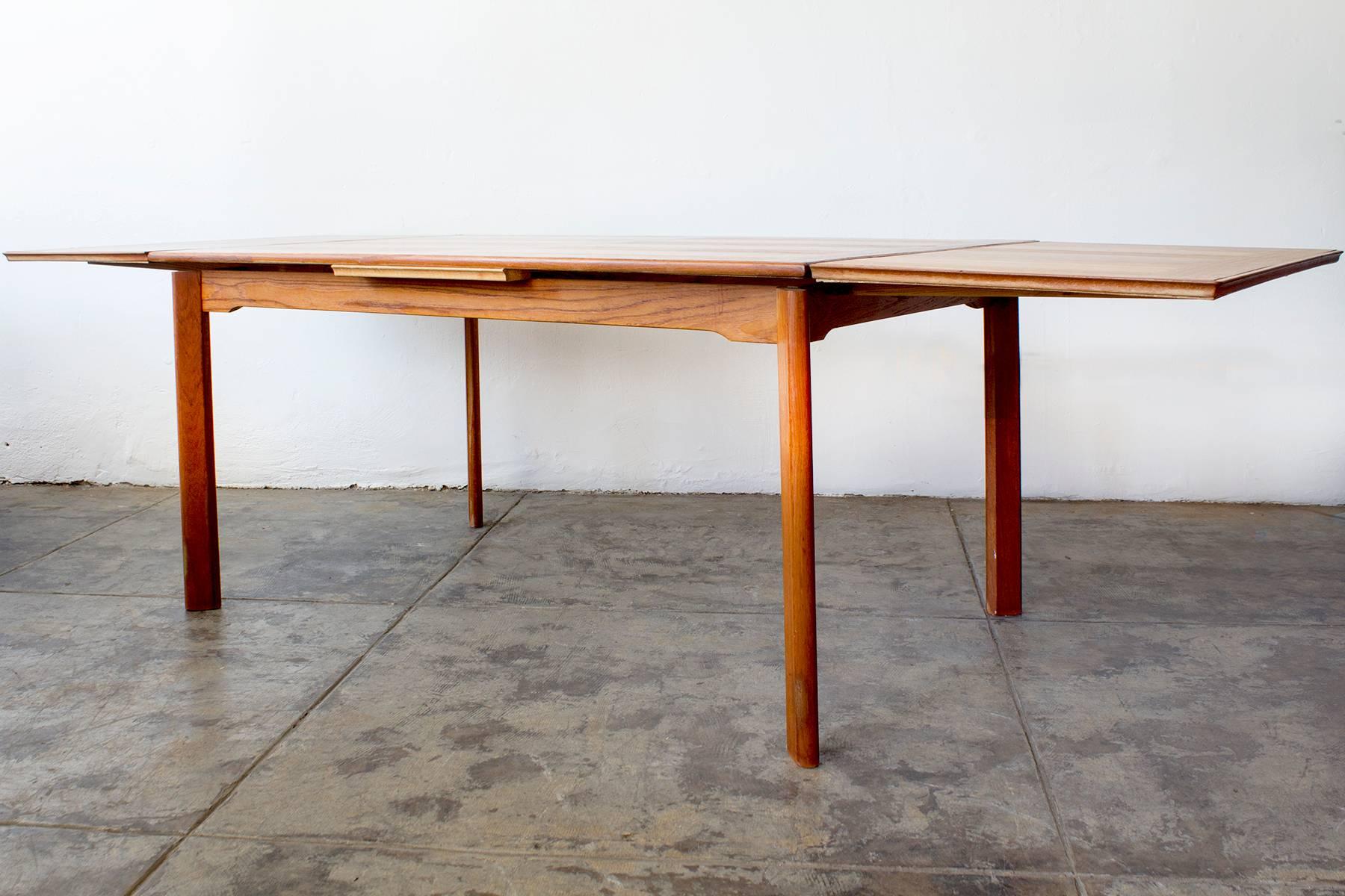 Beautiful Danish modern teak dining table with expanding leaves and statement angled legs. Stamped "Denmark." Designer unknown; in the style of Arne Hovmand-Olsen or Johannes Andersen. 

Dimensions: 34.5" D x 54-74" W x