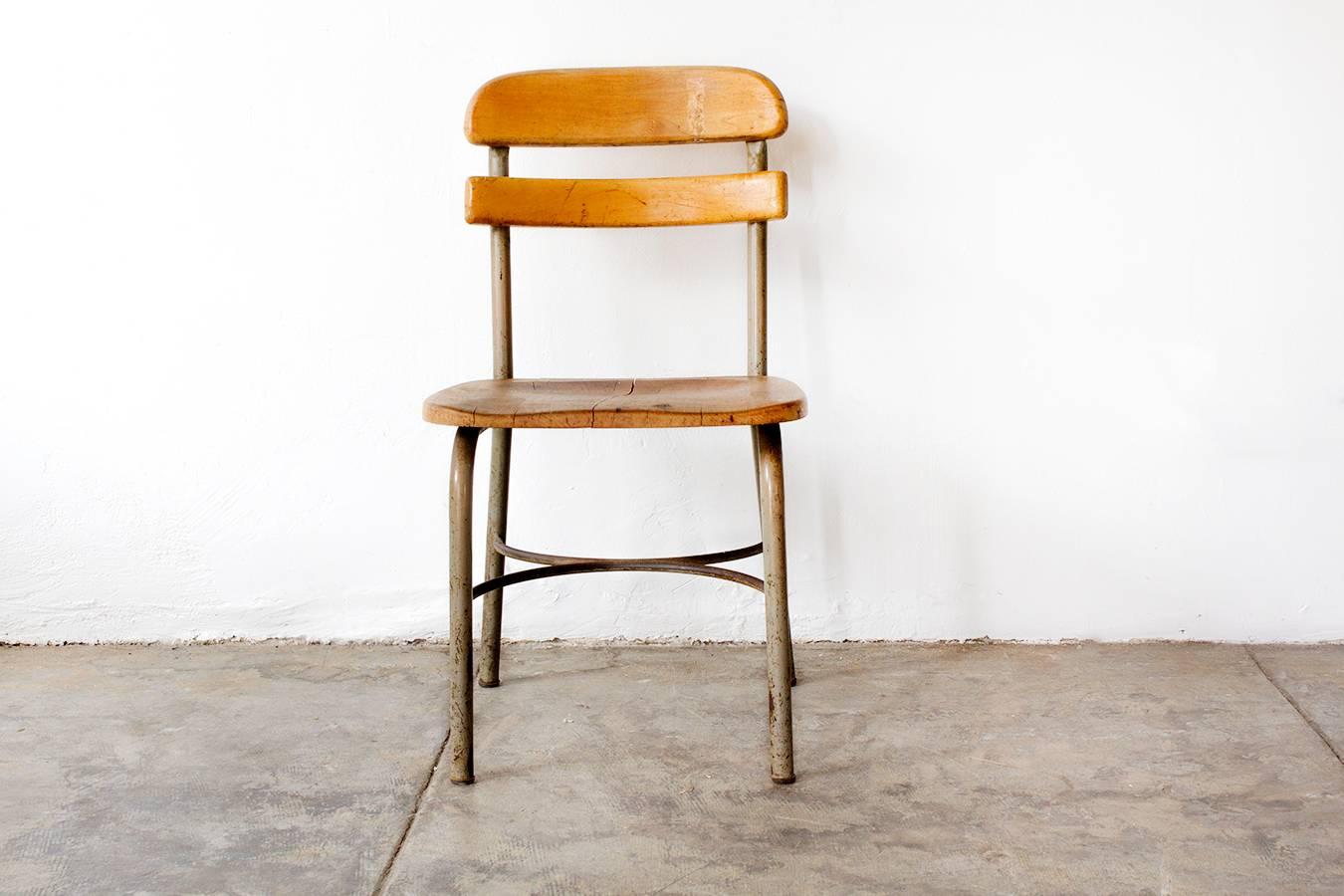 Uncommon 1950s child's school chair composed of heavy gauge tube steel frame and wood seat. The wood slat back and semicircle book rest make this piece a winner. Both steel and wood show original vintage patina. Wood has been gently reconditioned.