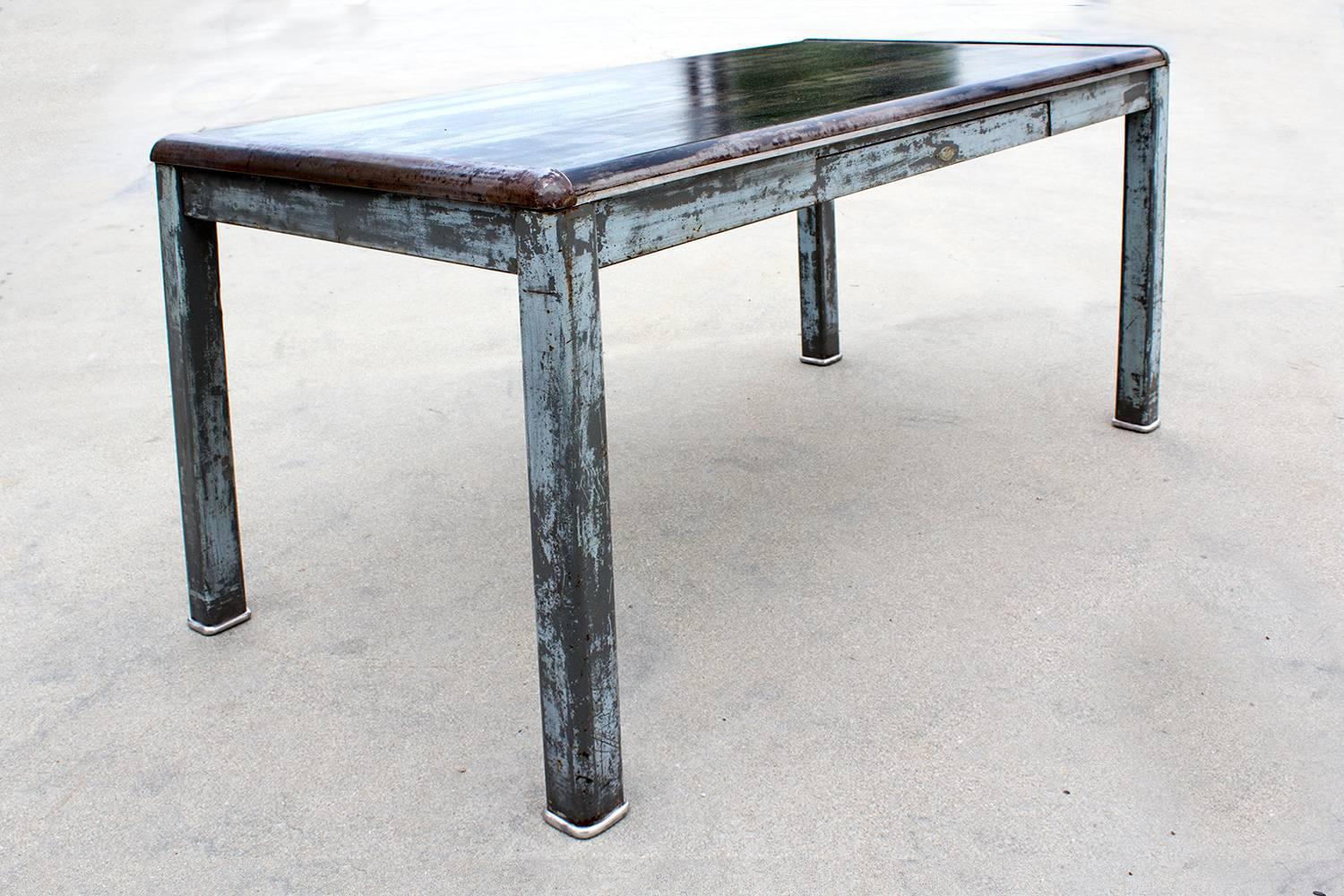 Fantastic art metal tanker table, circa 1940. We refinished this uncommon piece with a distressed patina finish. Tabletop includes unique rounded steel end-caps and utility drawer. 

Dimensions: 60
