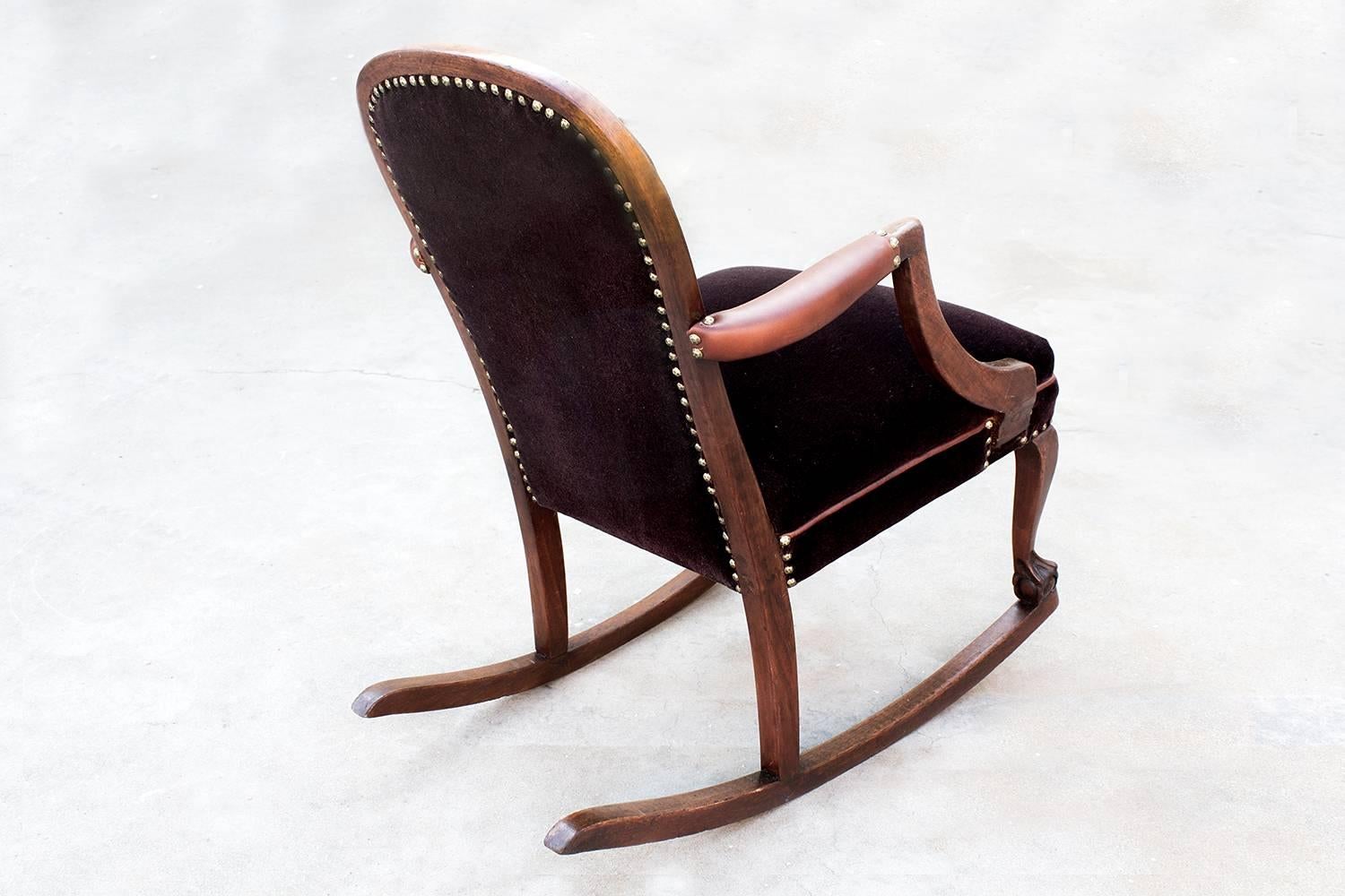 Beautifully refinished American Empire style rocking chair, reupholstered in a deep brown mohair with caramel brown leather arm covers and seat piping. Solid oak frame, reconditioned. This unusual antique rocker pairs soft curves with decorative
