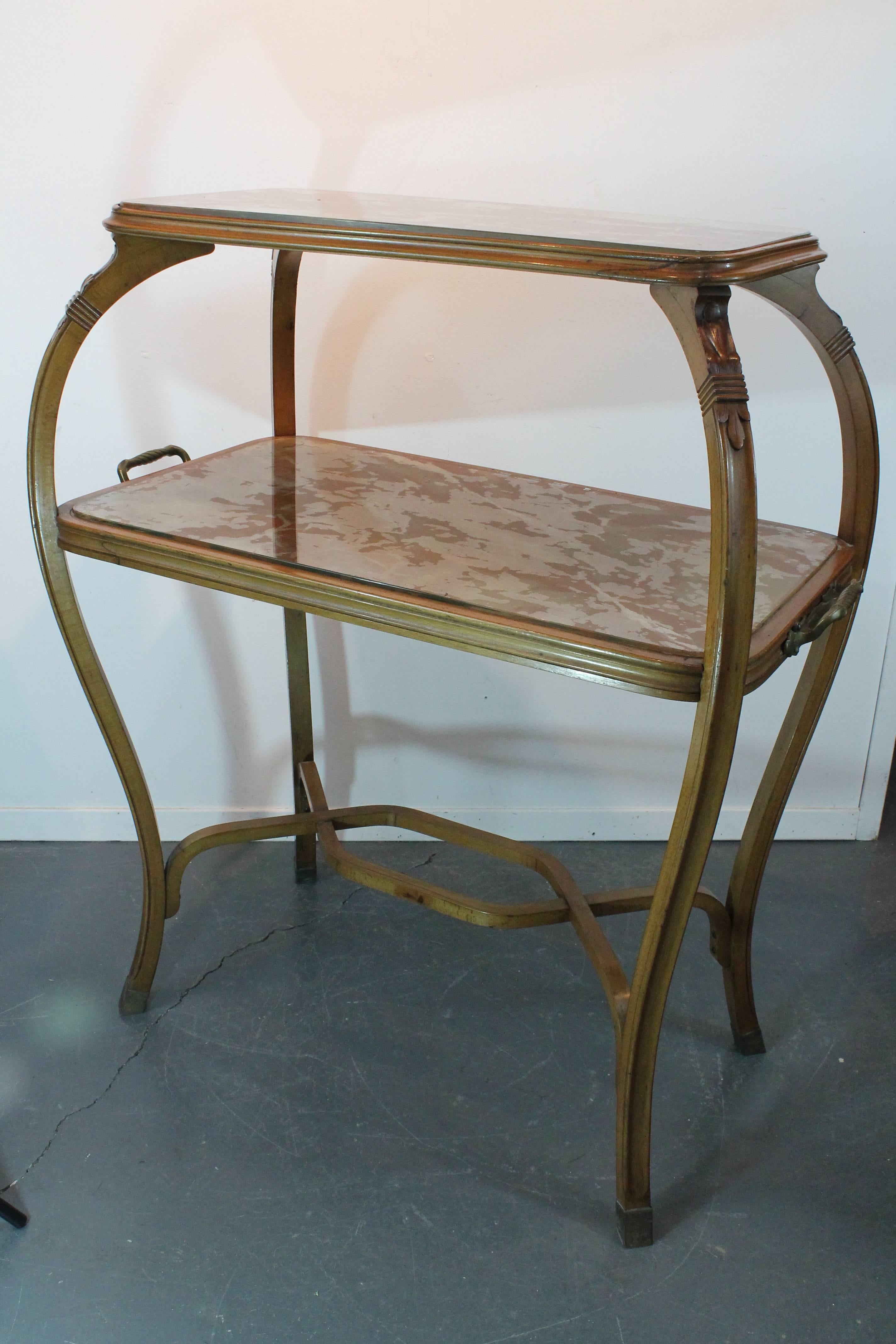 Very elegant lines and details on this Art Nouveau fruitwood two-tiered étagère.
Graceful bowed legs with floral carved details and brass handles and capped feet.
The glass tops are faux marble reverse painted.
Would make a wonderful bar cart.