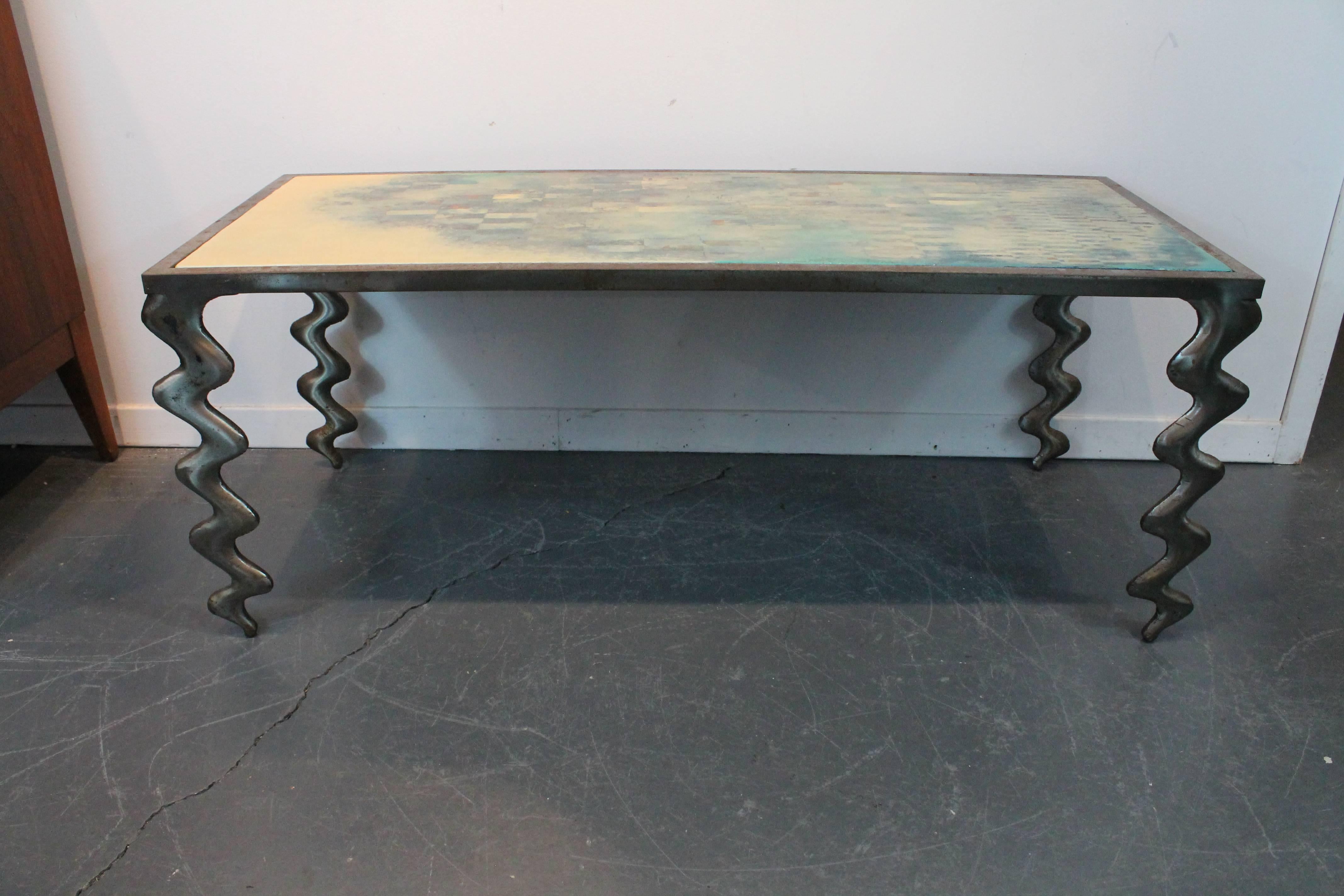 Iron sculptural cocktail table with a painted wood Modernist top. 
The tabletop rests inside of the iron frame and features a wonderful Modernist grid like composition.
Signed on the bottom of the table top 