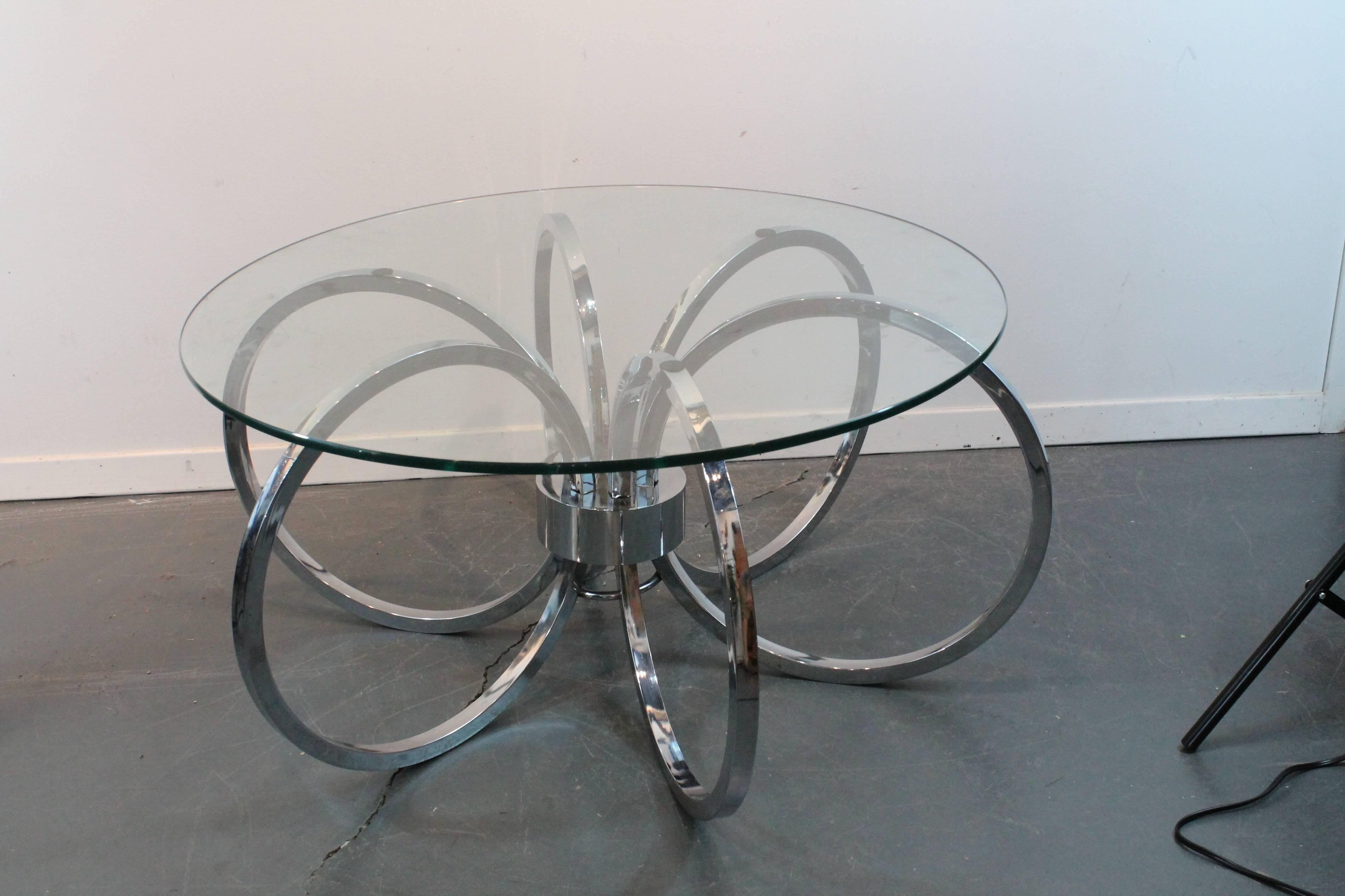 Sculptural chrome cocktail table consisting of six rings with a central chrome axis.
The glass top measures 30
