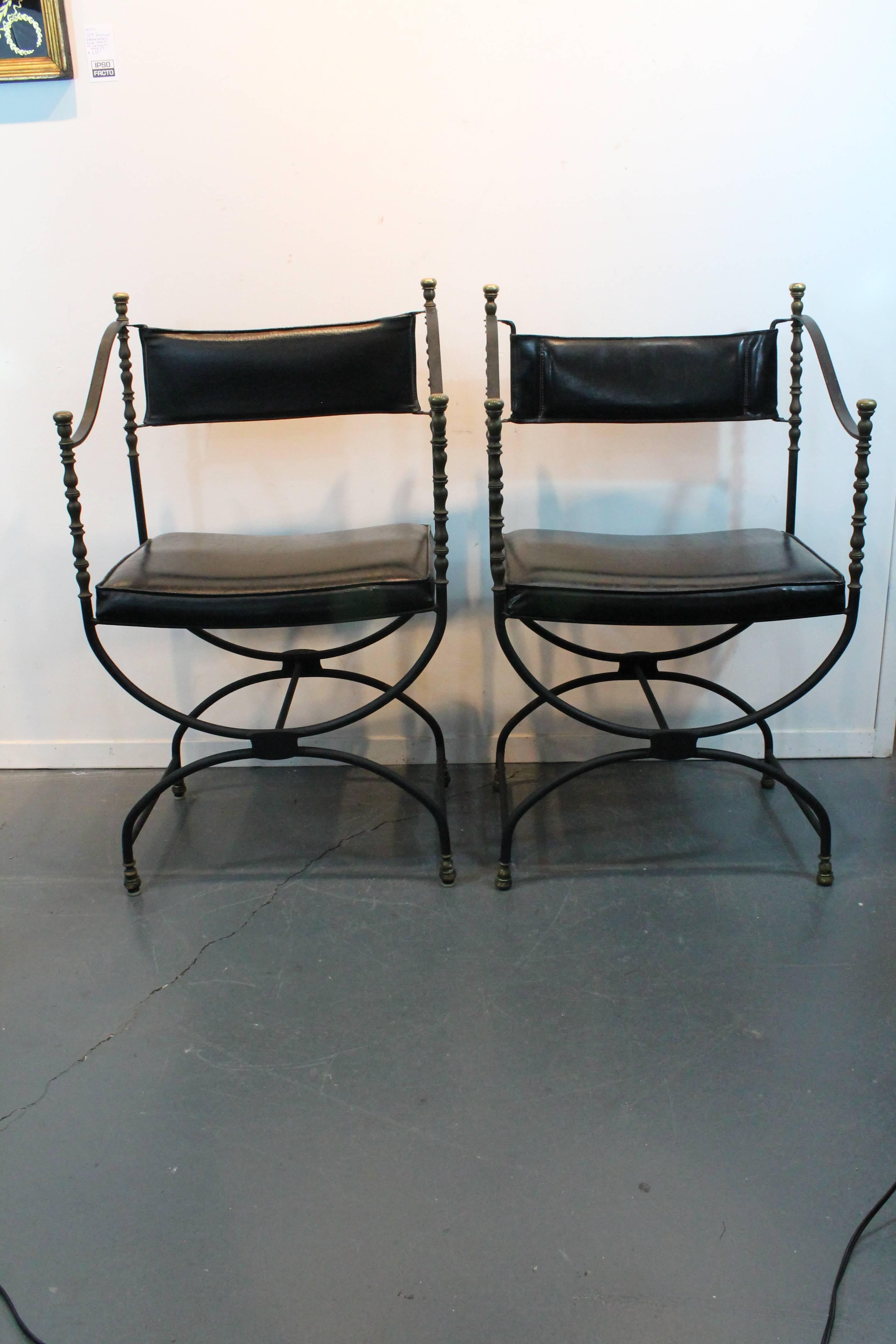 Great sculptural Savonarola armchairs.
Iron form with brass feet, finials and columns.
Vinyl seats and backs. There are two chairs that have a different back vinyl construction from the other two, as shown in close up images.