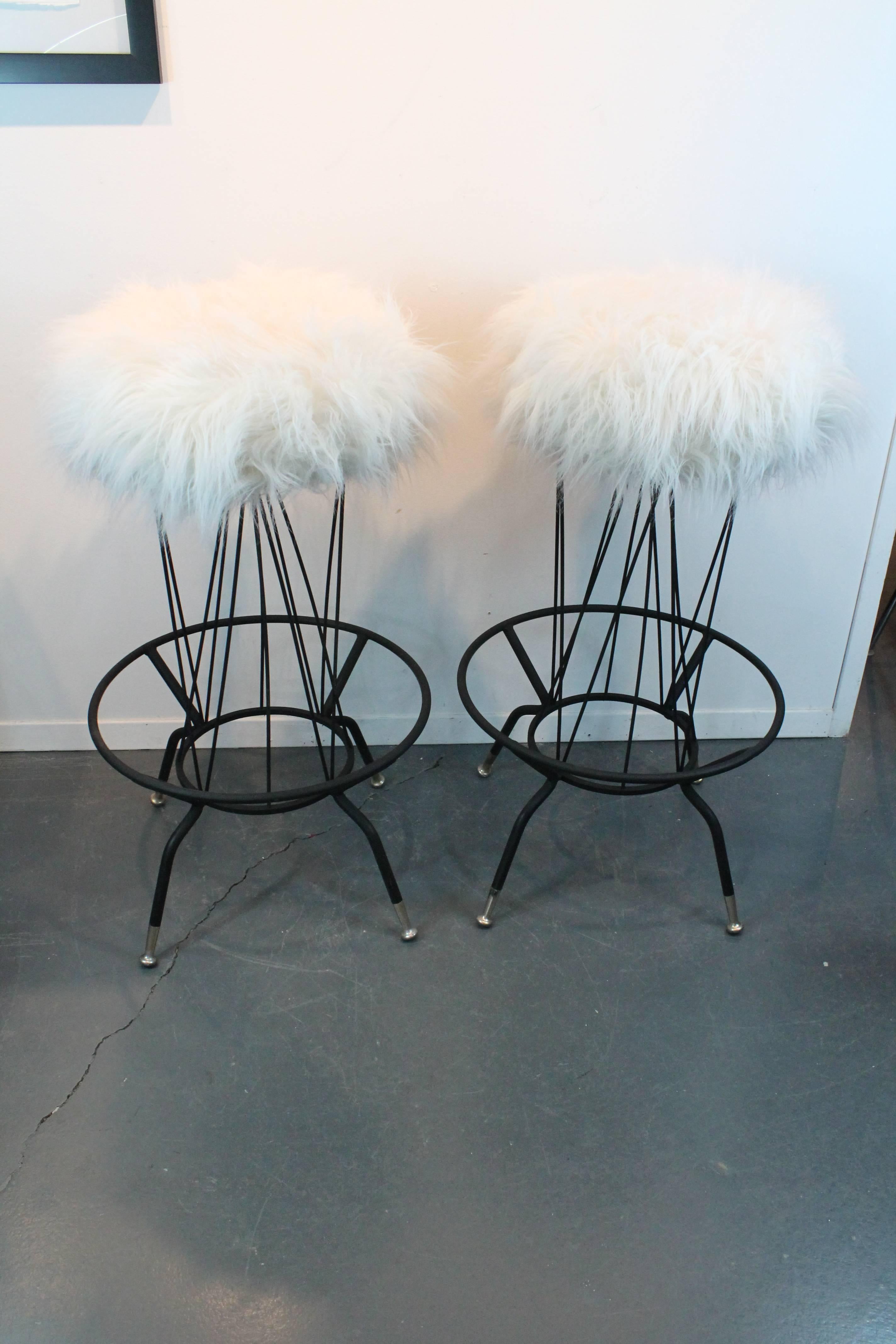 Great sculptural lines on this Mid-Century Moderne pair of swiveling barstools, newly reupholstered in faux fur.