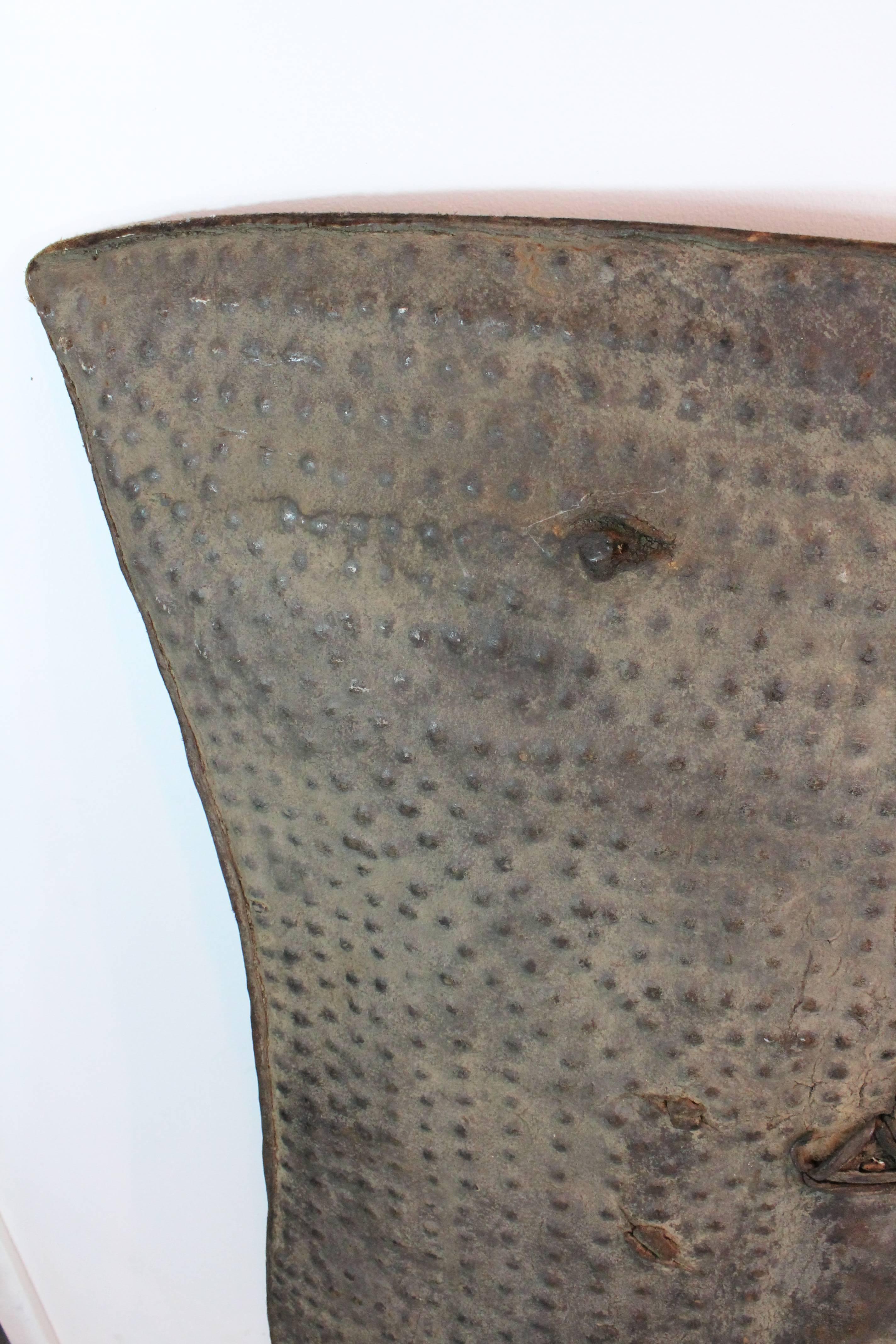 Powerful graphic large-scale embossed thick hide shield.
Excellent patina, age and usage on this thick hide shield from Ethiopia.
This beauty has battle wounds, there are two areas of old repair and a pierced section at the top.
Fantastic simple