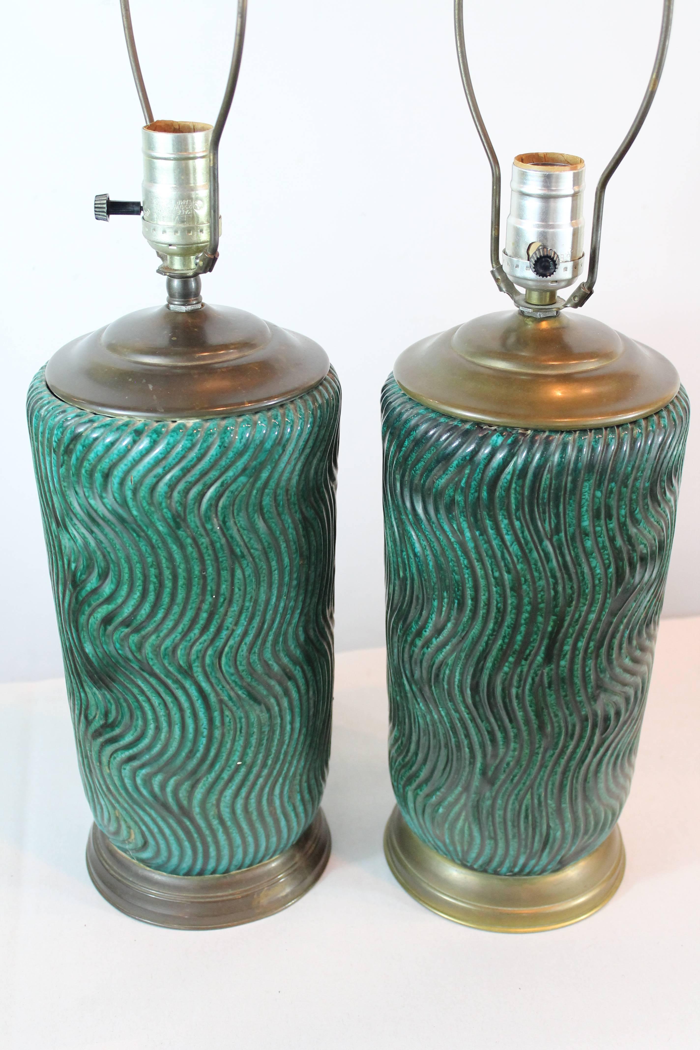 Remarkable flowing wave designed ceramic pair of lamps featuring a wonderful green variegated glaze.
The brass bases are slightly different in design and the patina is darker slightly on one of the lamps.
No finials or shades included.