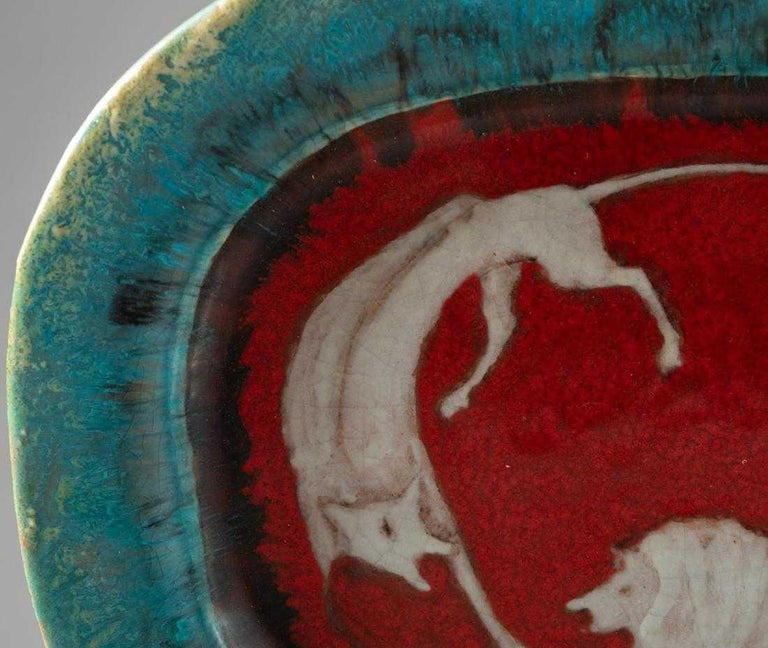 An Italian art pottery charger by Professor Eugenio Pattarino circa 1950s. The platter can services as a large centrepiece and it features a thick and contrasting glaze with mottled green rim and crimson centre background where a male and a female