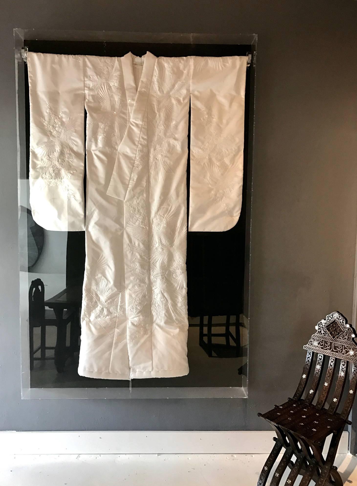 A vintage Japanese ceremonial kimono, circa 1940-1950, beautifully framed and displayed in a Lucite shadow box. An unusual white on white ceremonial piece in pure silk with intricate embroidery work that depicts cherry blossom, peony flowers, cranes