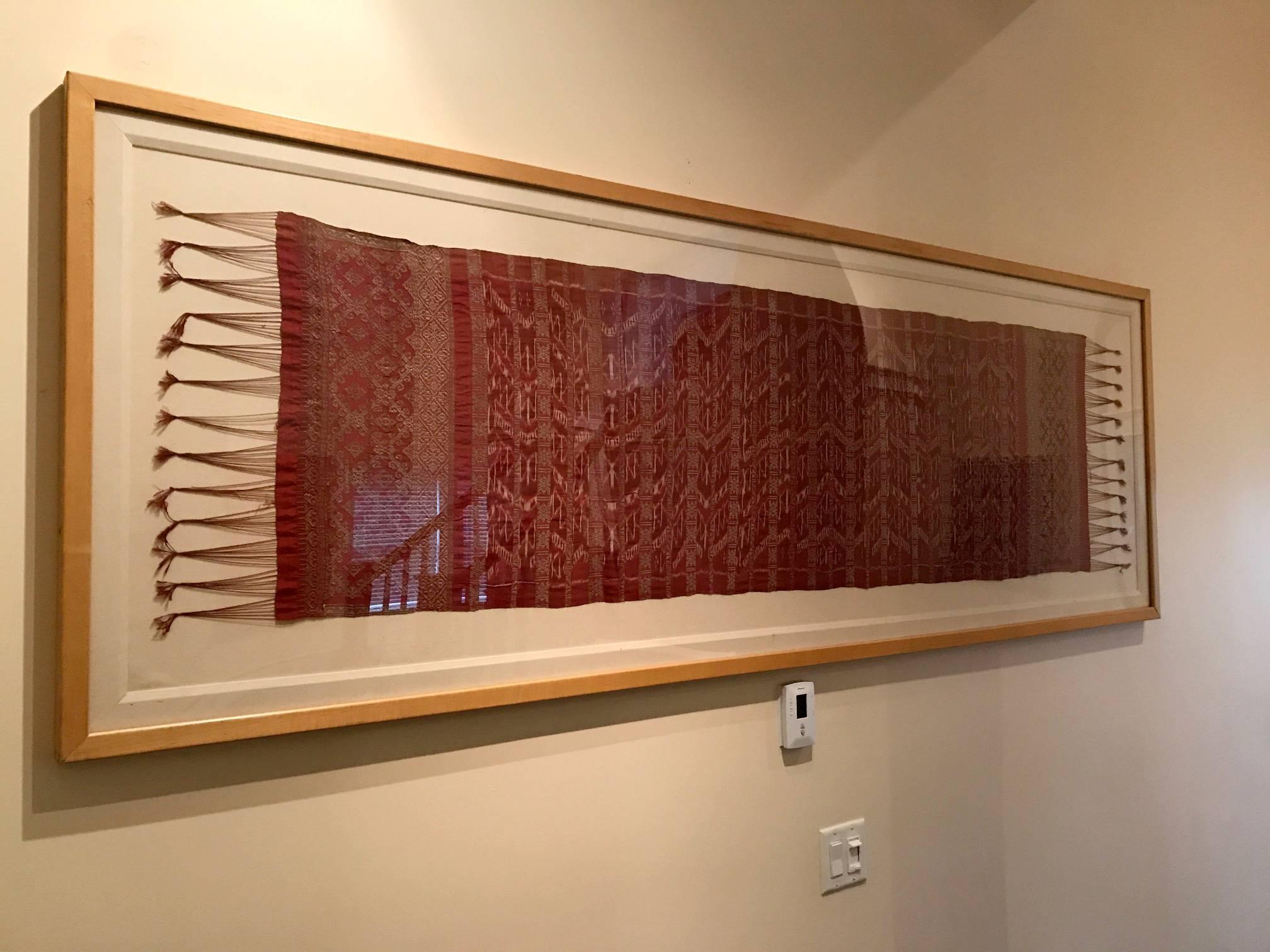 Ikat en soie magnifiquement tissé avec des franges aux deux extrémités, collecté dans la région de Jingaraia sur l'île de Bali en Indonésie, vers le début du 20e siècle ou plus tôt. Le textile présente des motifs en zigzag de couleur rouge, argent