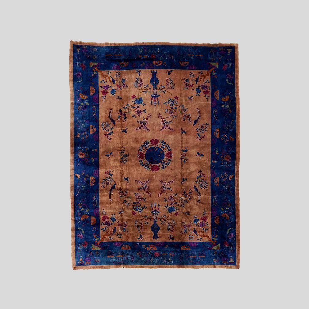 A hand-knotted Chinese Art Deco Rug circa 1920-30s in fine vintage condition. Likely made in one of Walter Nichols' factories in China, the rug features a pleasant soft mink colored field with a dark blue central medallion and main borders, the rug