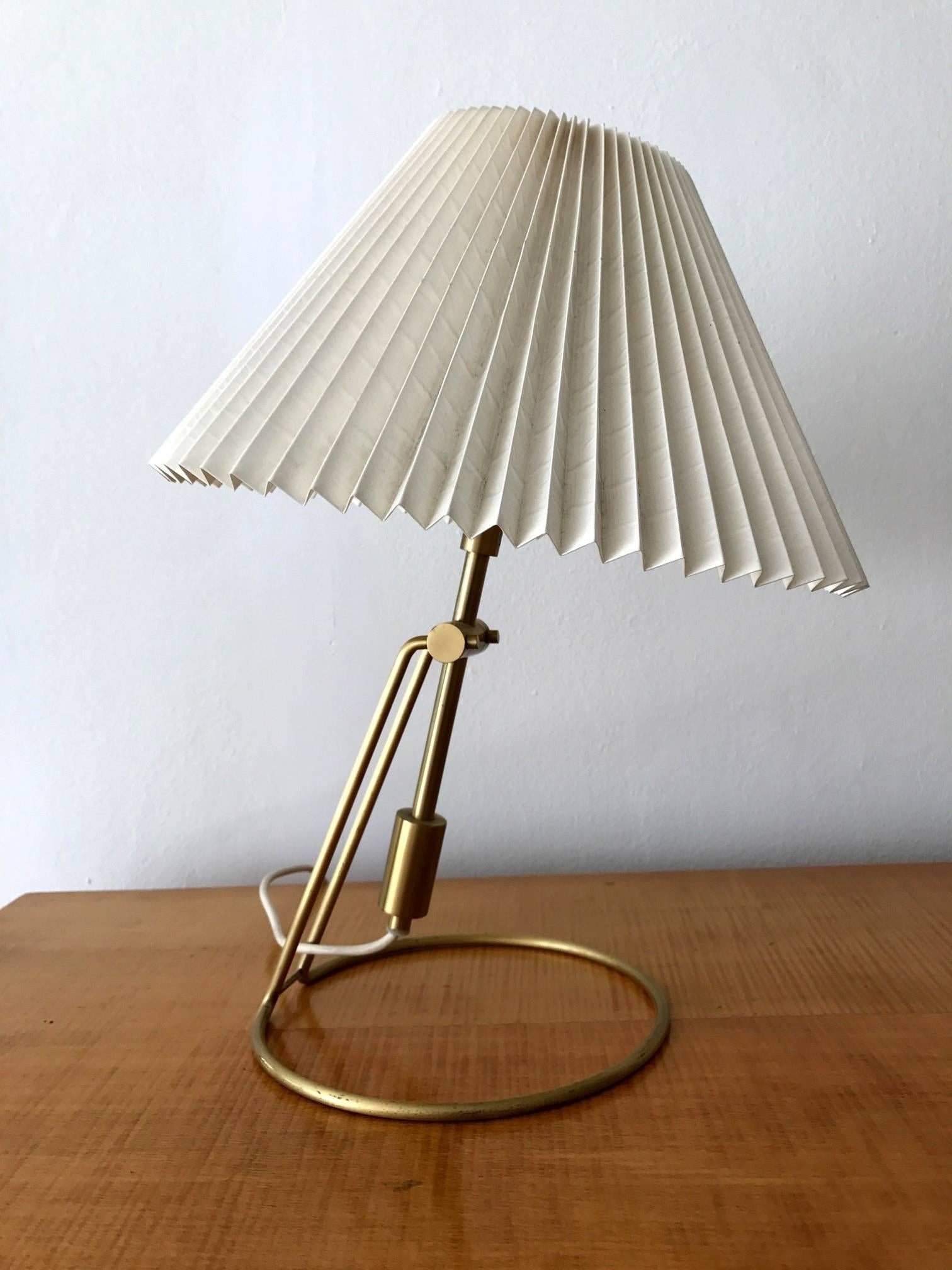 A pair of brass table lamps with original folded cellulose shade by Danish make Le Klint. The lamp sits on a very architectural base that can be tilted to an angle for different lighting direction. Model 305 and signed decal manufacturer's label Le