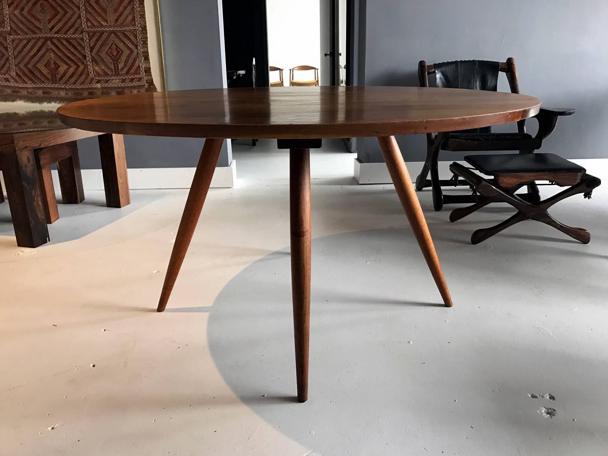 A circular dining table made from American walnut with spindle legs by George Nakashima, circa 1960s-1970s. Minimalism Mid-Century Shaker-like design that showcases woodwork based on traditional Japanese techniques. Residual pencil marks underneath