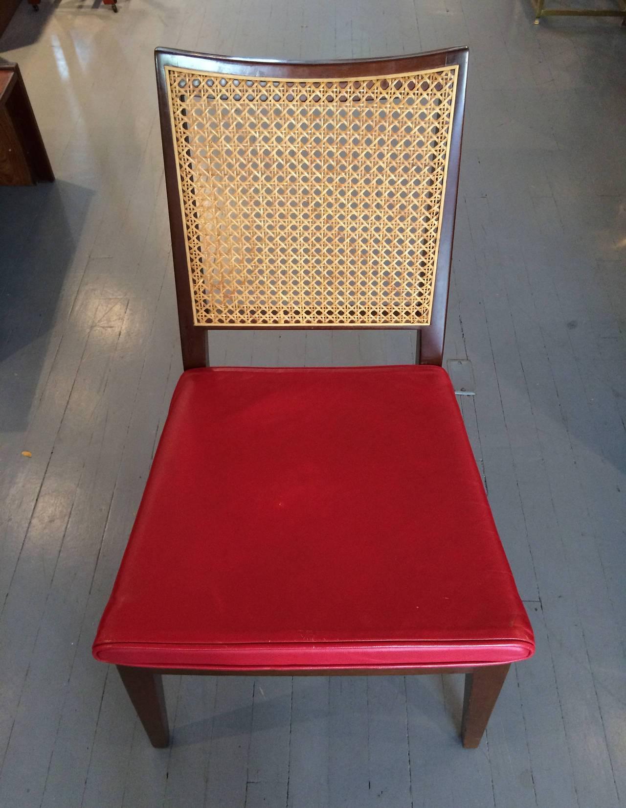 A pair of walnut side chairs by Edward Wormley for Dunbar. Red leather cushion on solid wood seat with slightly curved caned back. Simple and elegant form with a Japanese sensibility. One of the chair still retains Dunbar brass tags underneath as