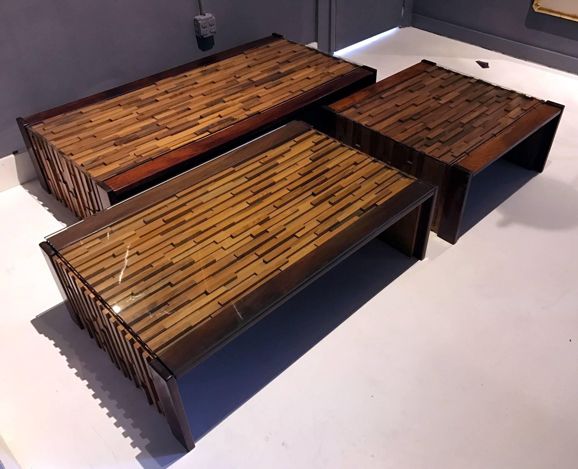 A set of three Brazilian coffee and side tables by Percival Lafer. Highly sculptural design with blocks of rosewood, jacaranda and mahogany construction in a slight Brutalist manner. It consists of three different sizes. The largest is 30 by 59, the