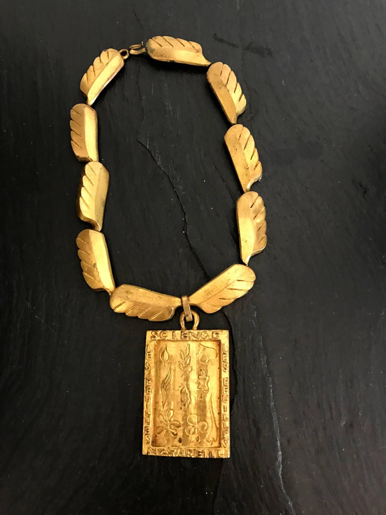 A beautiful gilt bronze necklace with feature design links and a pendant by French jeweler Line Vautrin, circa 1940s. Bronze leaf pattern linked chains attached to a square plaque pendant, on which one can find many botanical leaf motif and