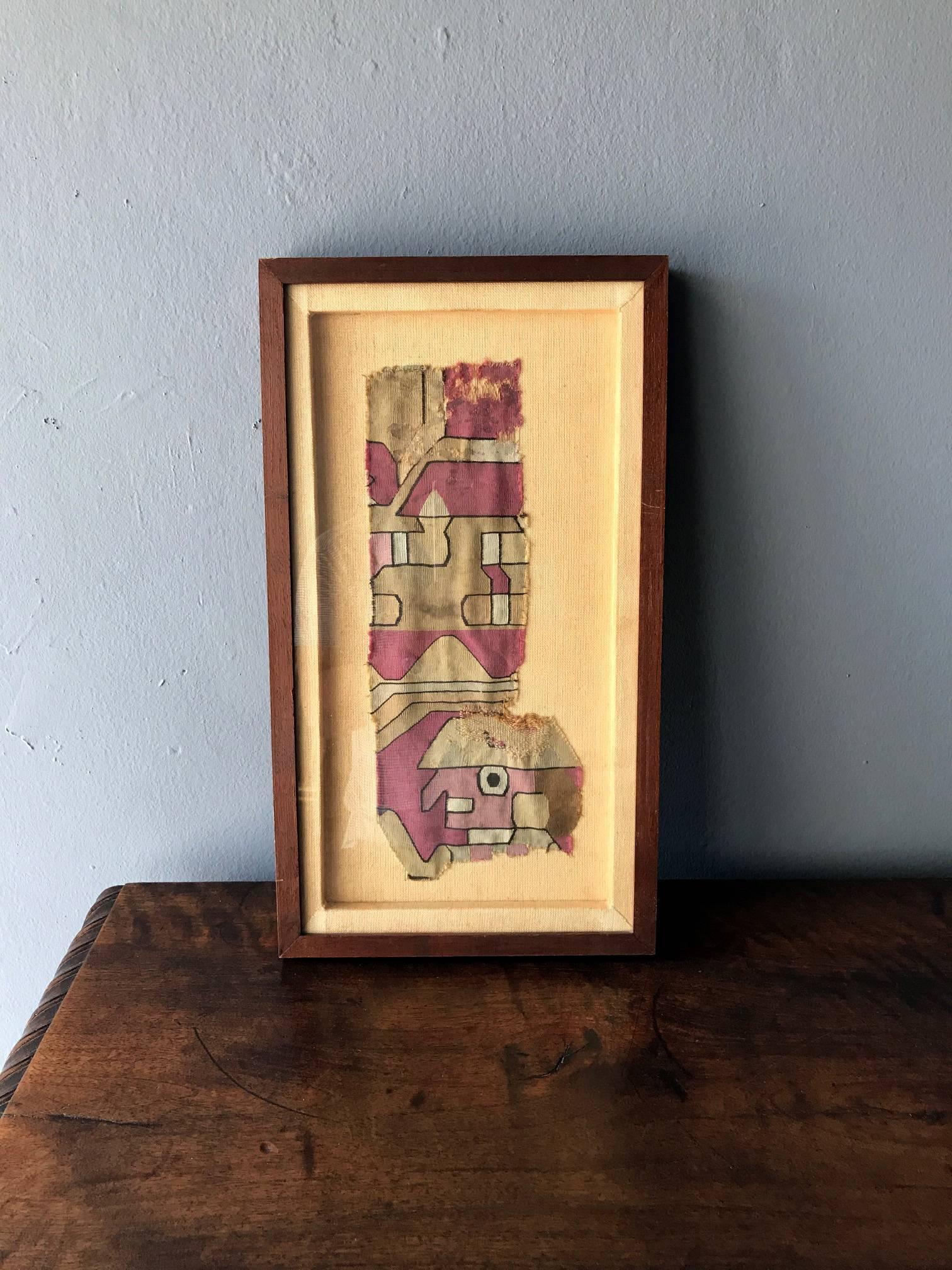 A nicely framed fragment of antique Pre-Columbian textile that depicts a stylized figure in a geometrical background. Linen backing. The original is likely from Inca empire and nowadays Peru.