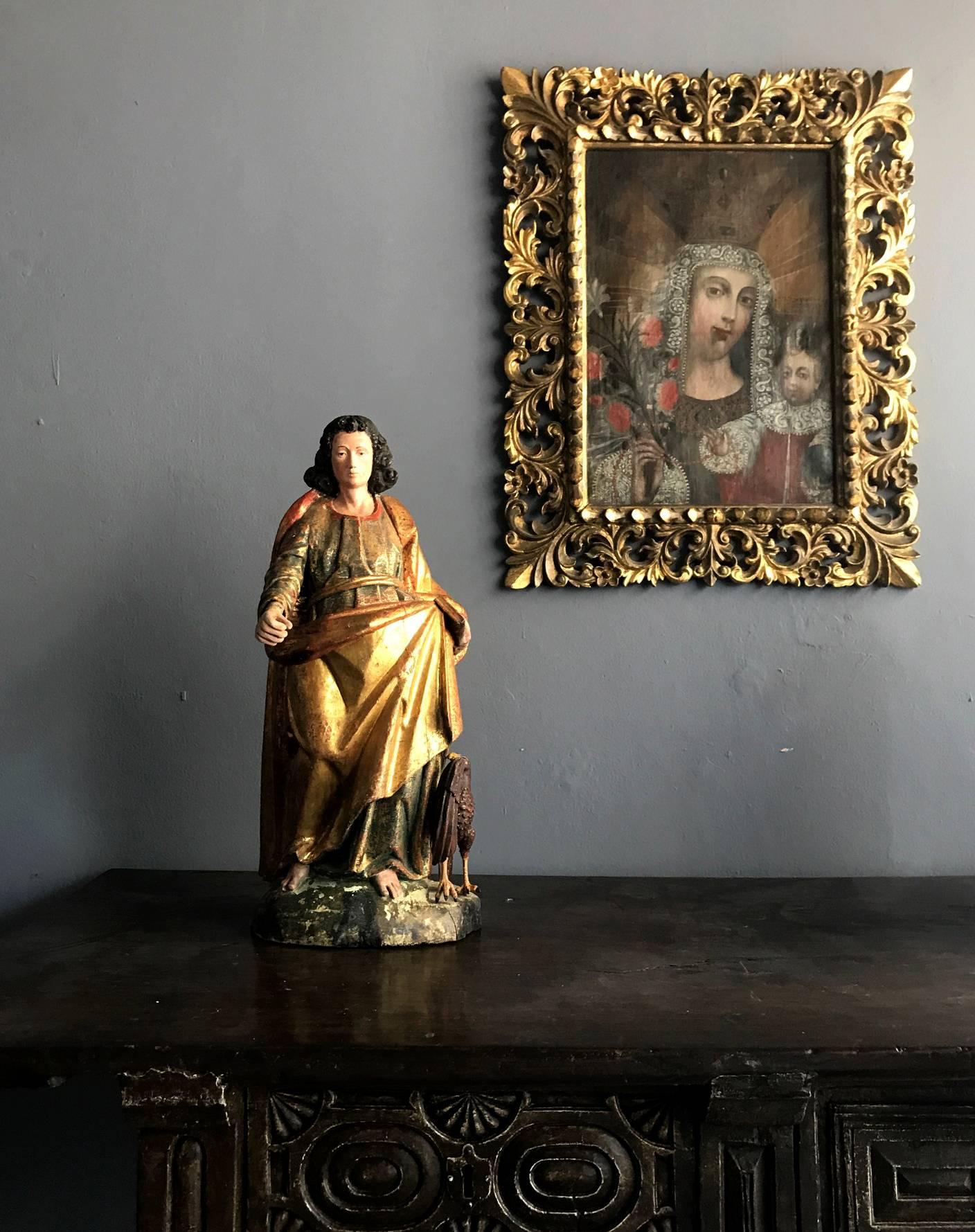 Superbe statue de Saint Jean en bois doré, XIXe siècle, peut-être plus tôt, provenant du Mexique, de style colonial espagnol, avec un décor de peinture polychrome. Saint Jean est représenté comme une figure royale avec des robes drapées, un bras