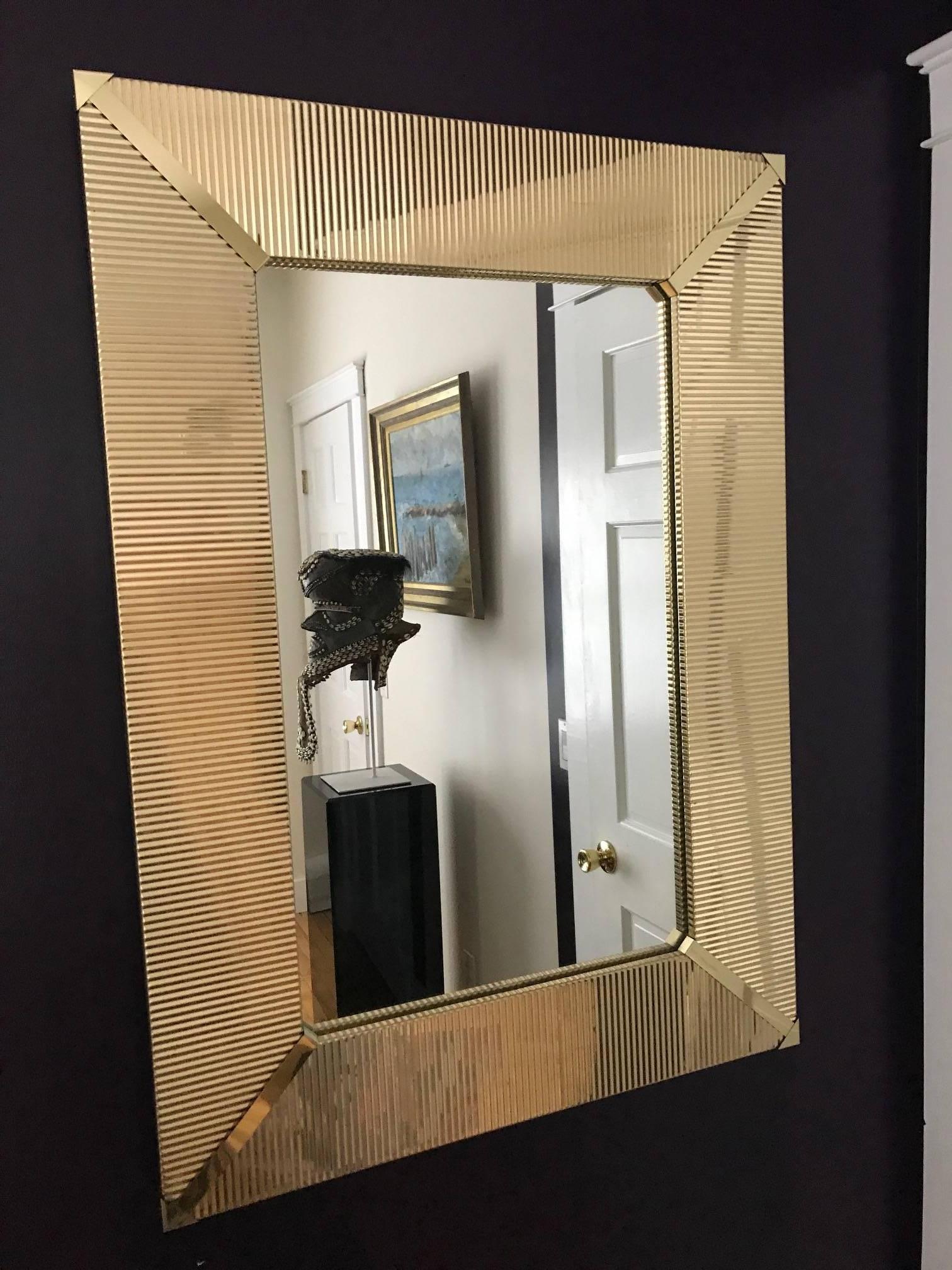 A very groovy and well-made wall mirror made of wood and brass circa 1970s. The brass frame features a corrugated design with corner trim pieces. Oversized and heavy and will make a bespoken piece in any room.