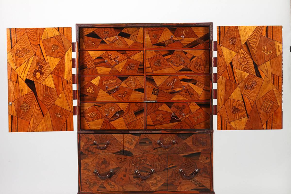 A piece of functional art made in Shizuoka for export to the western market, this Japanese chest with drawers on stand, circa 1900s features intricate marquetry work using a traditional technique called Yosegi, which involves painstaking inlay and
