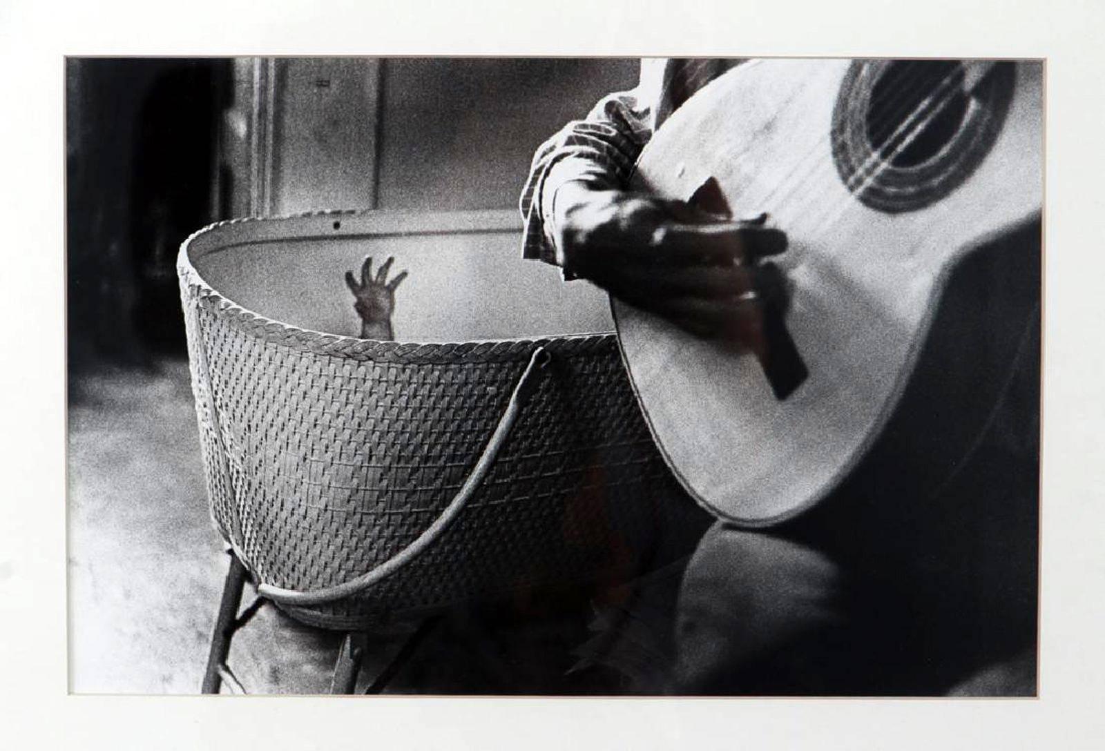 A vintage gelatin silver black and white print by American photographer Gibson Ralph (born 1939, Los Angeles, CA),
Untitled [Guitar Player & Bassinet]
Dated 1961, 7 of an edition of 25
Gelatin silver print
Measures: 8 x 12.25 inches (sight