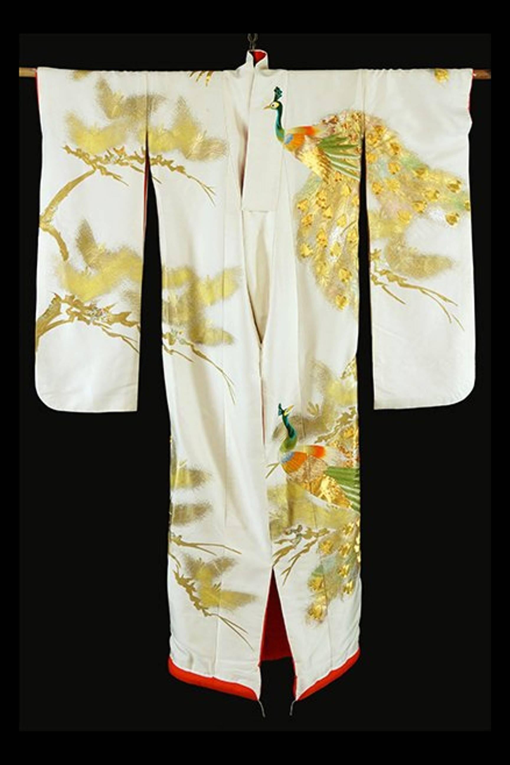 A truly exceptional Japanese ceremonial kimono, circa 1930s in Oriental Art Deco fashion. White silk background with elaborate and intricate embroidery in color and gold threads that depict auspicious symbols such as the pines trees and peacocks