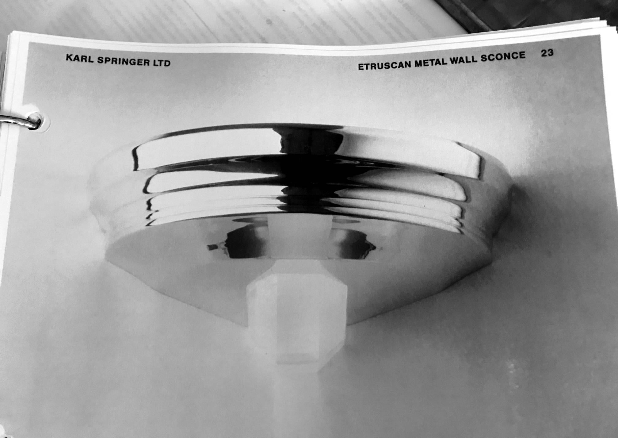 Pareja de apliques de pared etruscos diseñados y fabricados por Karl Springer, hacia la década de 1970. De acero cromado con Lucite opaco. Gran proporción con materiales y silueta modernos que interpretan la forma clásica. Evocan con glamour un