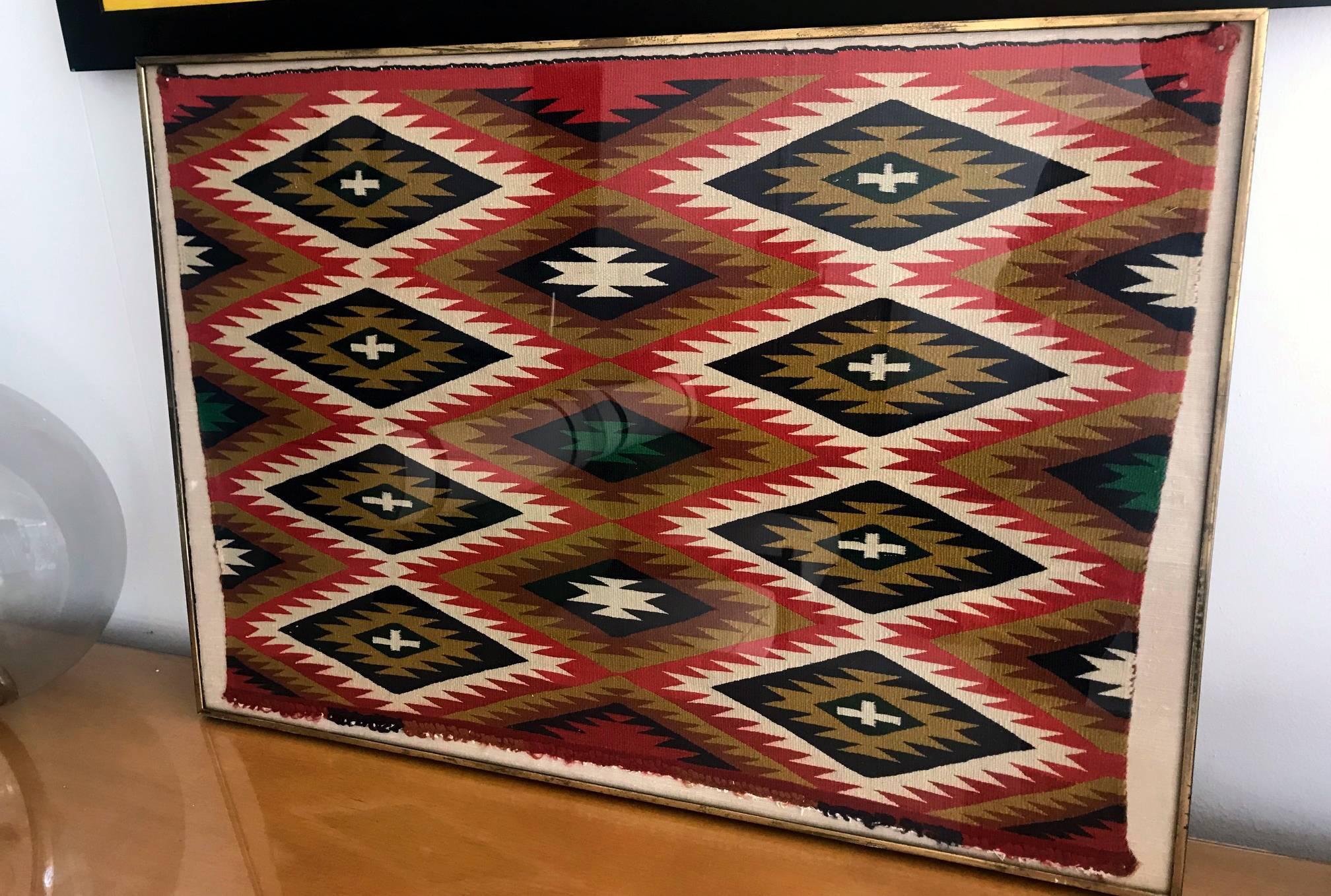A framed Navajo Germantown weaving in an eye dazzle style, very tightly woven with commercial Germantown PA yarns in multiple shades of red, green, blue and brown. Intended as a small saddle cover or sampler for historical tourists. High quality and