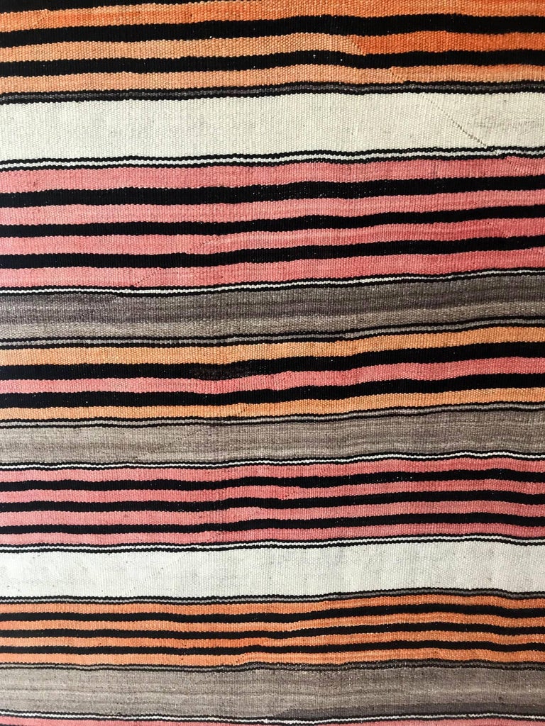 A banded utility blanket known as Diyog in Navajo circa 1880-90. The simple but elegant horizontal patterns consists of natural white, brown and black wool and dyed orange and red wool, all hand spun. There are lazy lines across the piece evident.