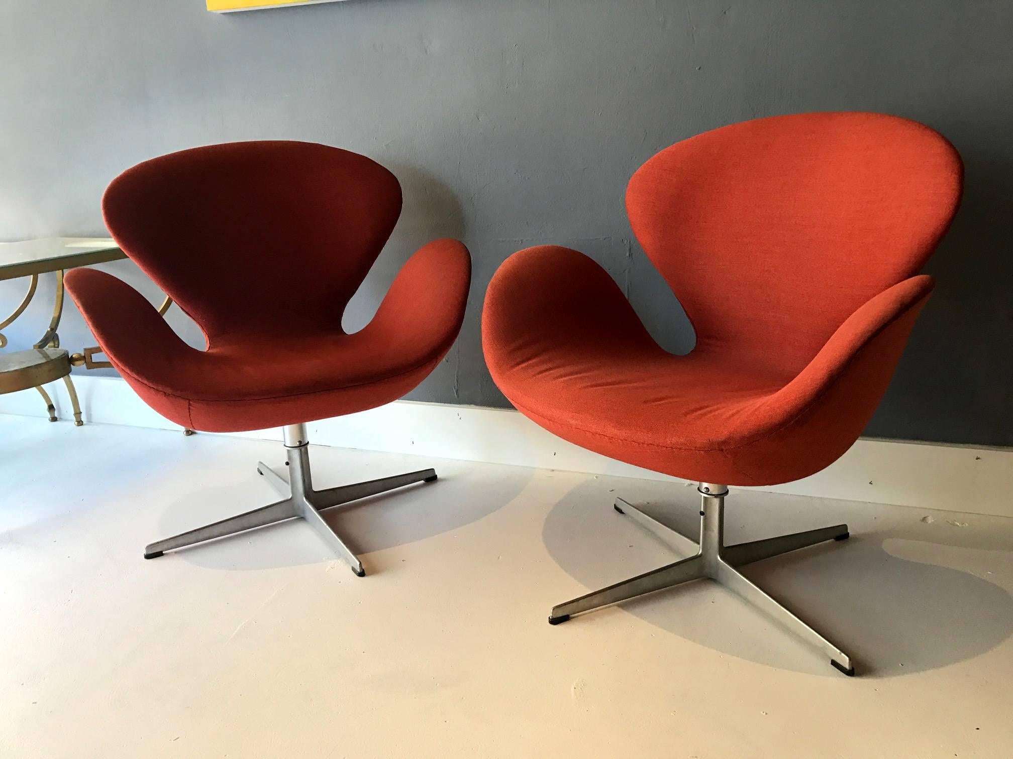 A pair of vintage swan chairs designed by Arne Jacobsen for Fritz Hansen. Iconic design with comfort and practicality. Earlier production by Fritz Hansen with brand mark and series number stamped on the base. Both swivel and upholstered in a