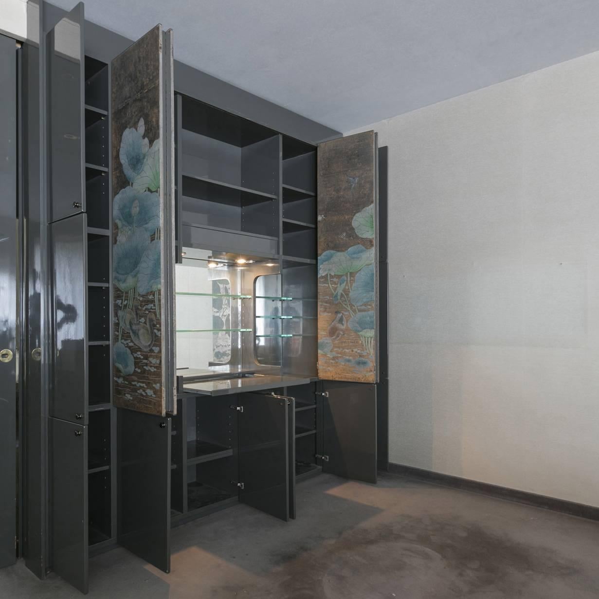 Remarkable dry bar cabinet by Luigi Caccia Dominioni for Azucena.
Custom-made piece features complete gray thick lacquered surfaces, glass shelves, two large folding doors with decorated panel.
The central area covered by the decoration has
