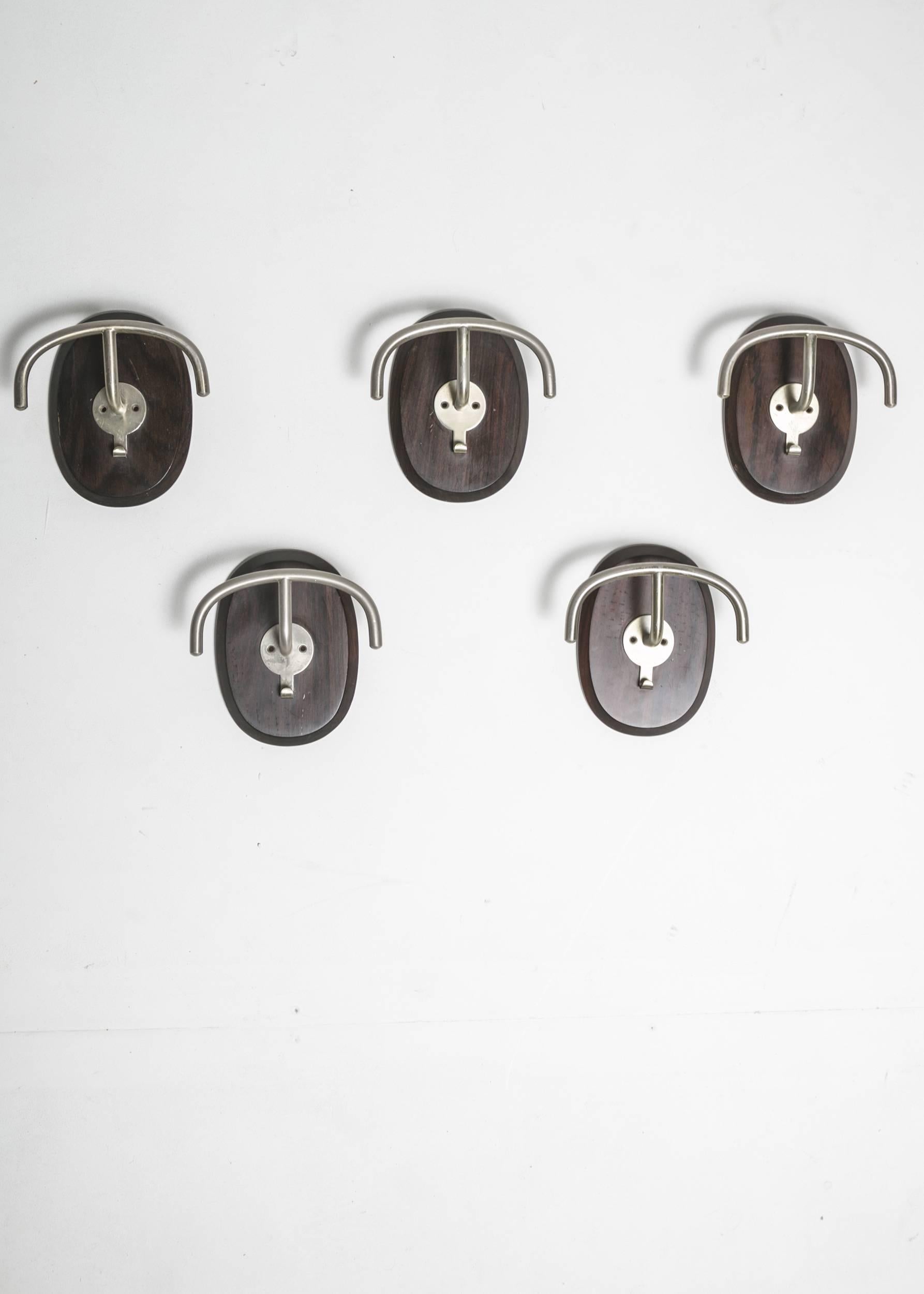 Set of five coat pegs by Emma Schweienberger Gismondi for Artemide.
Nickelled opaque brass and rosewood plate.