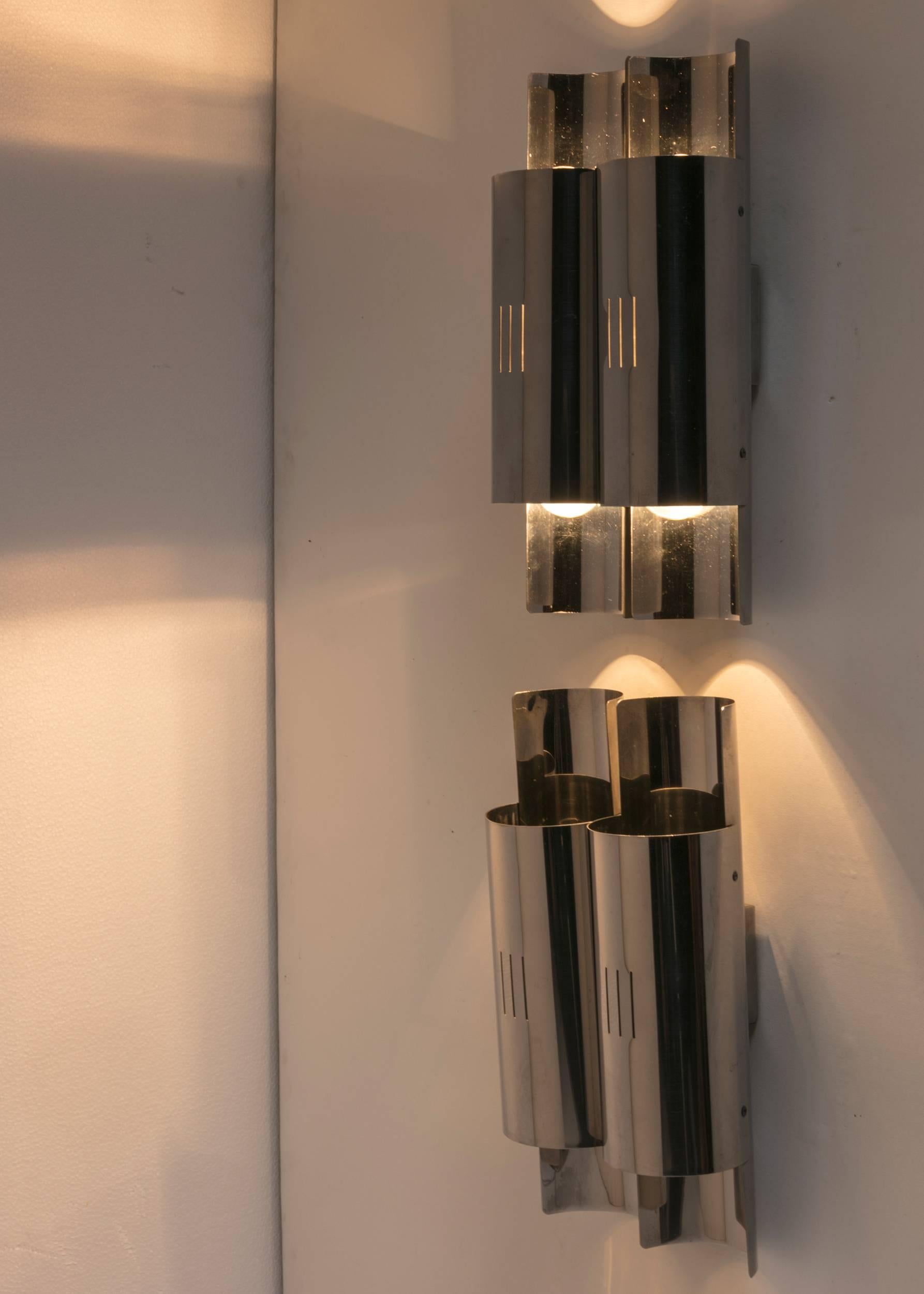 Set of two metal wall lights.
Each piece hosts four light bulbs partially hidden to create a soft and intriguing light effect.