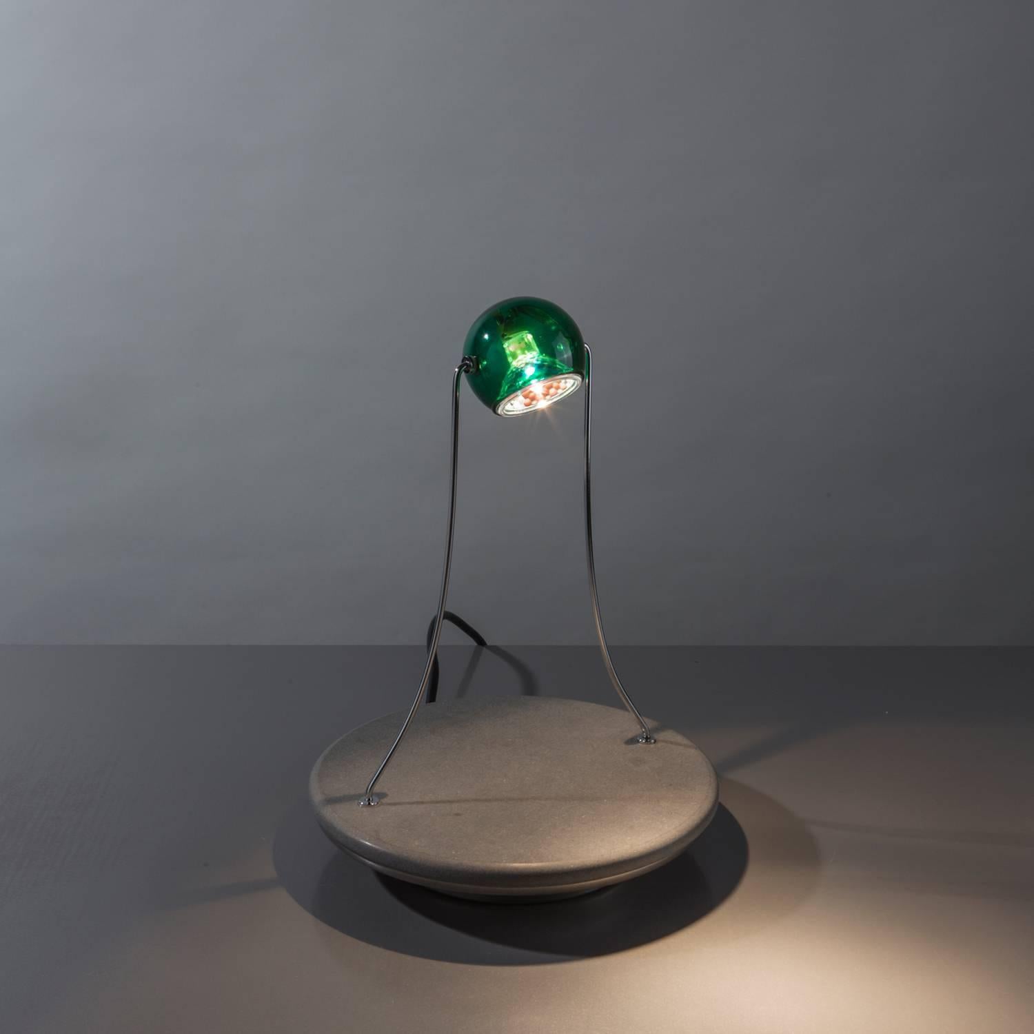 Heavy round Pietra Serena stone base and a green transparent revolving glass lighting head supported by thin chrome arms.