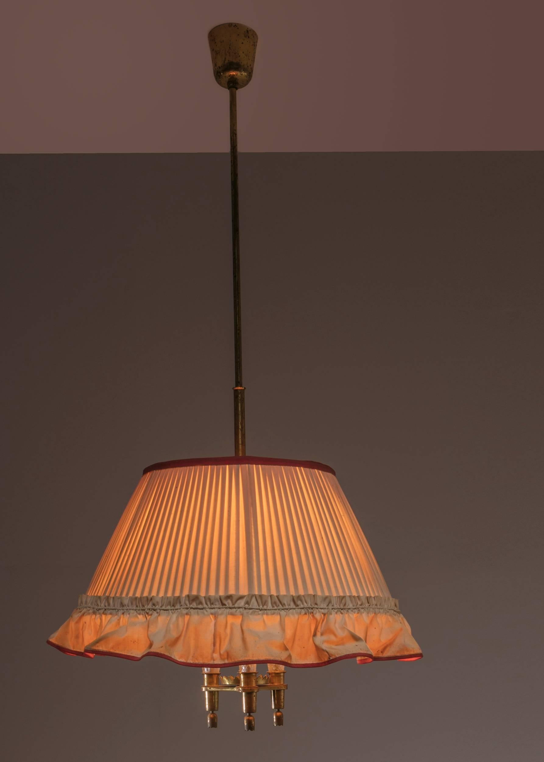 Italian 1940s pendant lamp manufactured by Strada, Milano.
The fabric shade hides three beautifully detailed light elements with brass and crystal elements.