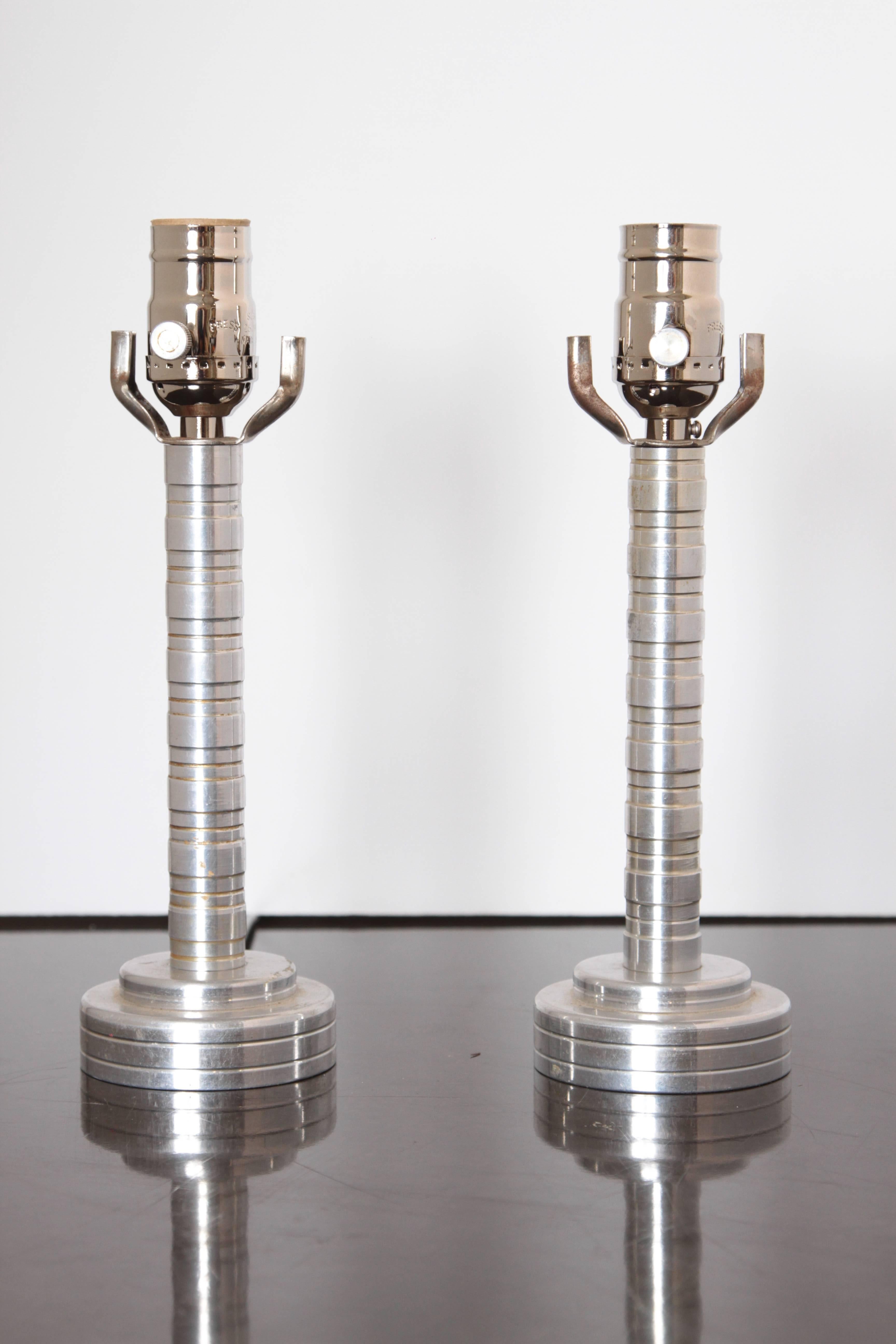 Machine Age Art Deco skyscraper pair turned, aluminium table lamps

Nice original functioning pair high-polish, engine-turned and incised aluminum desk or end table lamps.
Original chromed sockets with original aluminum twist knobs, rewired with