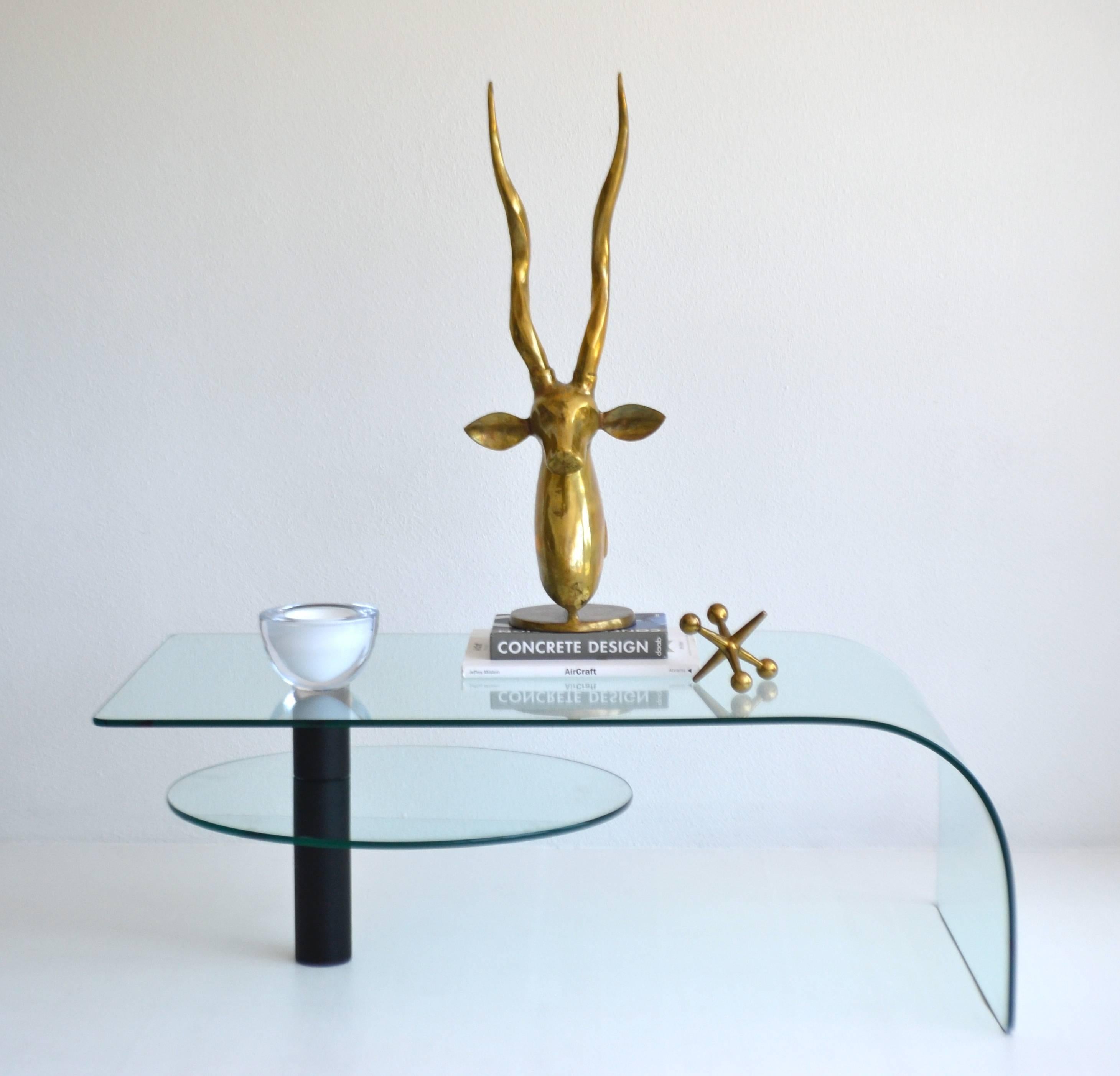 Sculptural Post-Modern two-tier waterfall edge glass cocktail table, circa 1970s - 1980s. This strikingly graphic articulating coffee table is designed with a black powder coated support column with a circular swivel lower tier glass table. 
Note: