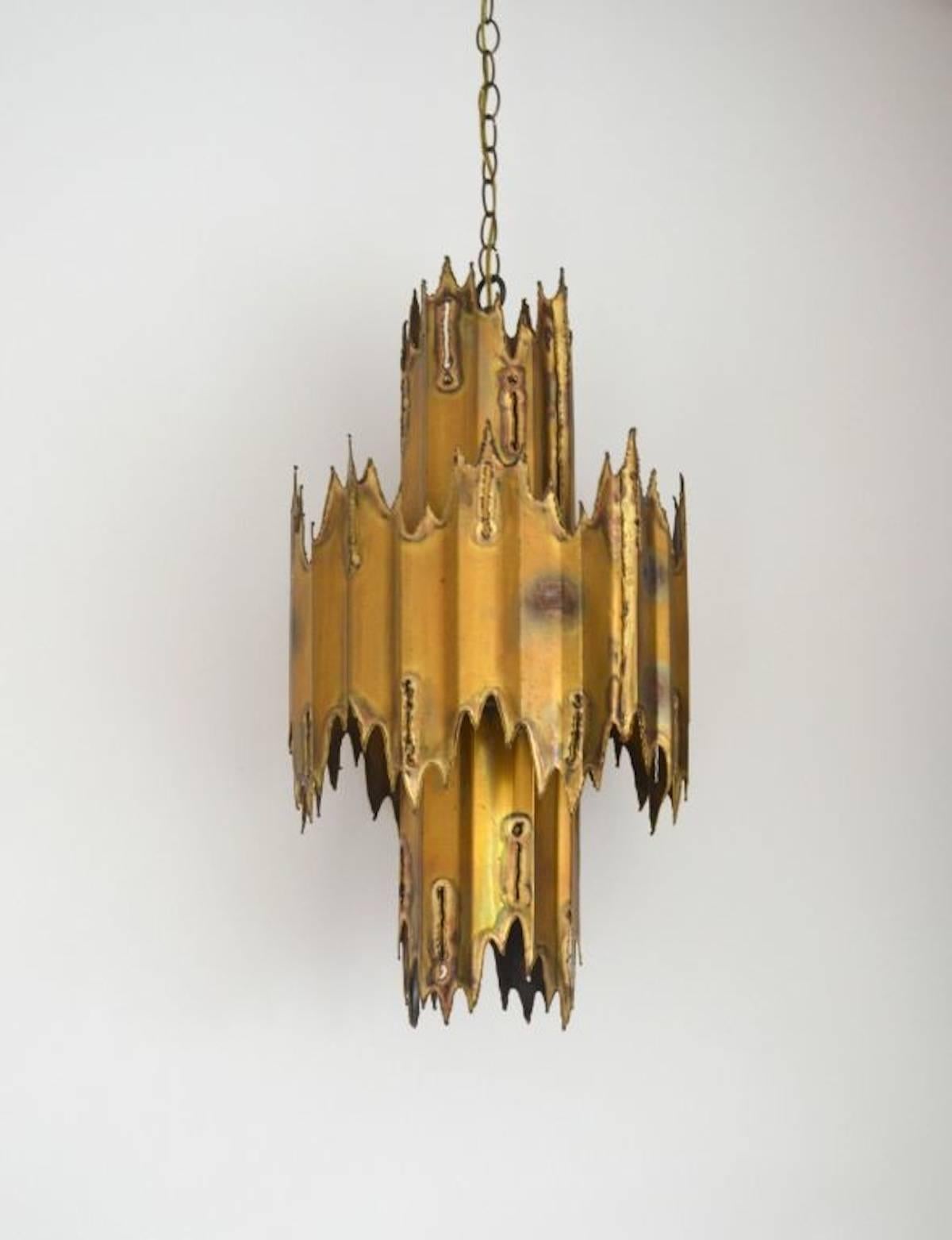 Striking midcentury Brutalist movement handcrafted torch cut patinated brass two-tier chandelier by Tom Greene, circa 1950s-1960s. This architectural and sculptural chandelier for Monteverdi Young features three brass sockets and one down socket.