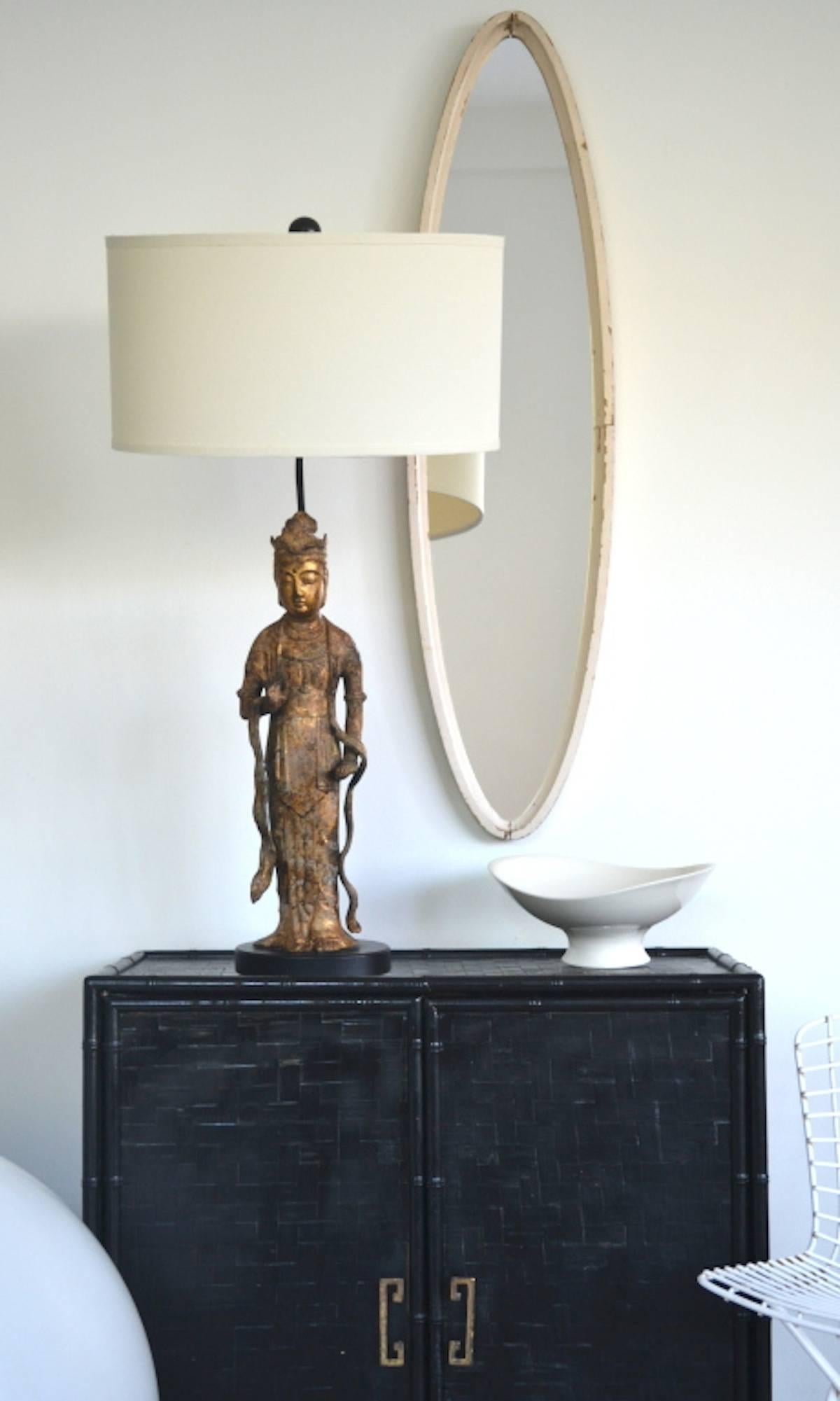 Glamorous Hollywood Regency gilt metal Asian Goddess figural form table lamp, circa 1940s-1950s. This stunning highly decorative lamp is mounted on an ebonized base and wired with brass fittings. Shade not included.
Measurements: The overall height