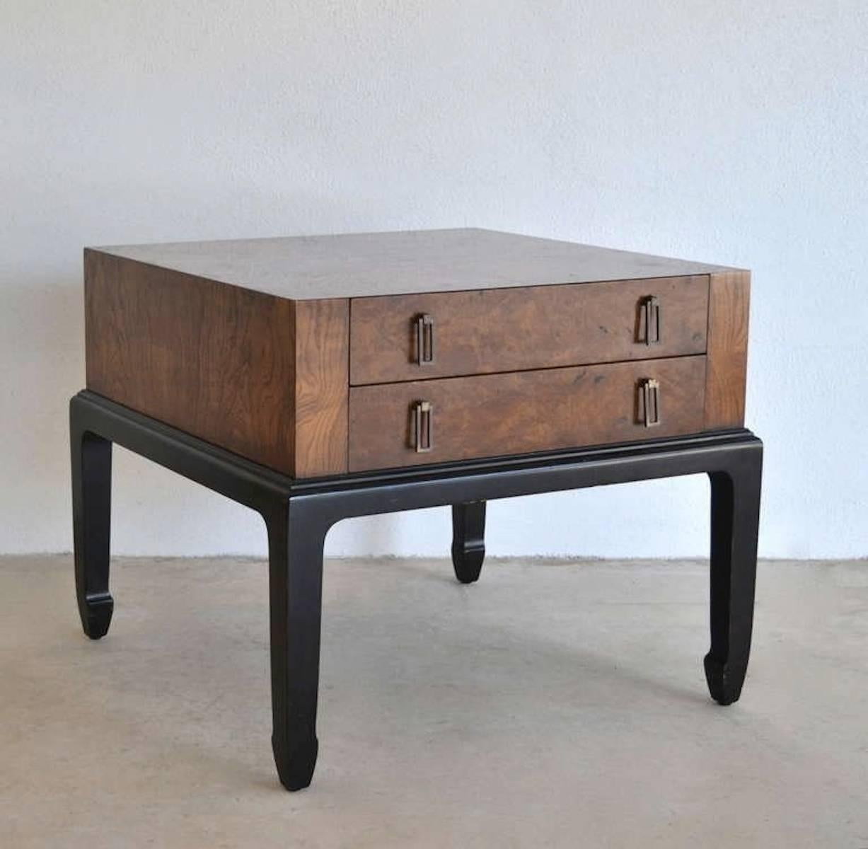 Striking midcentury burl wood side table, circa 1960s. This incredible nightstand is designed as a two-drawer chest mounted on an ebonized base and is accented with rectangular brass pulls.