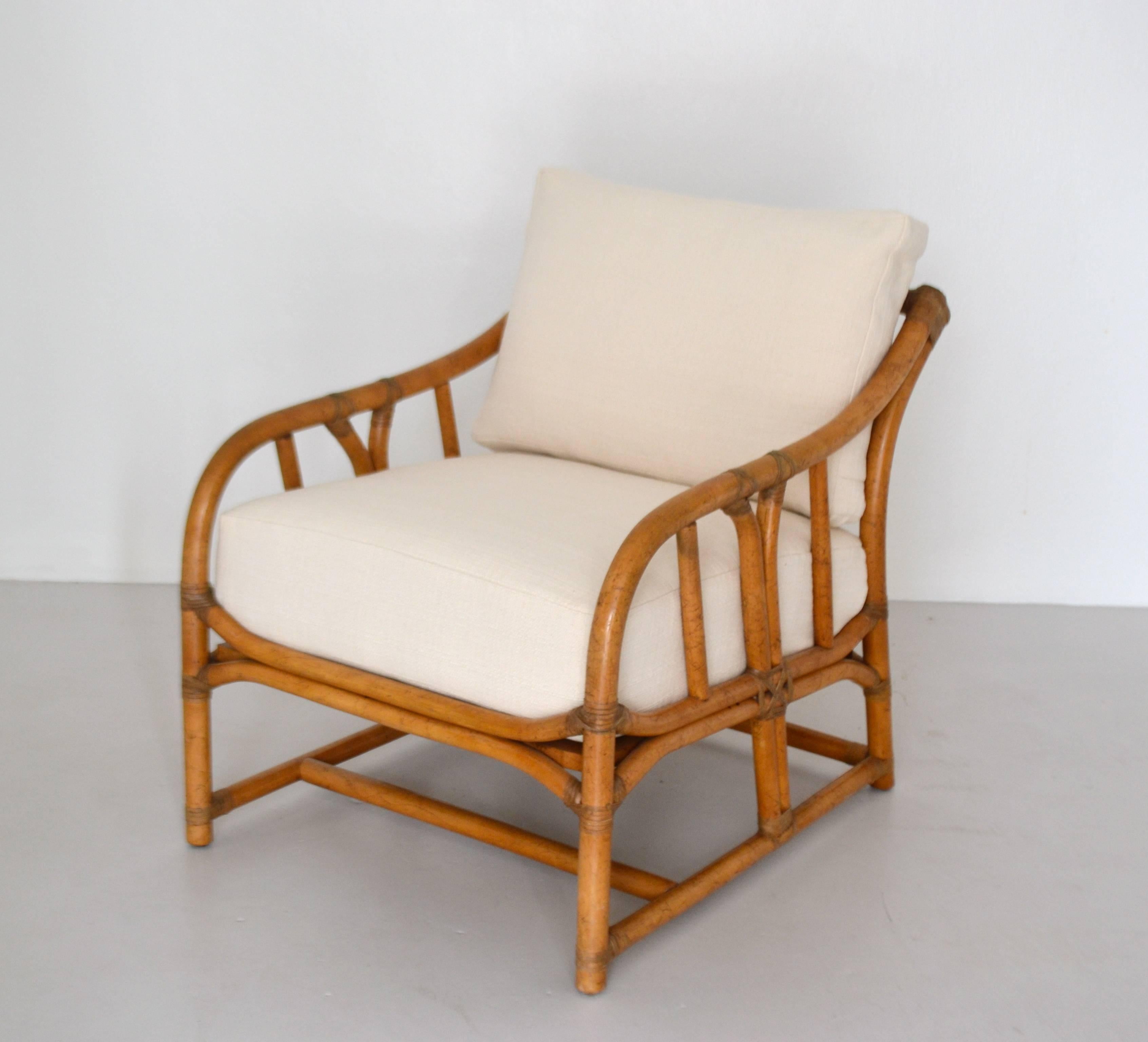 Glamorous pair of Mid-Century bamboo club chairs, circa 1960s. These striking artisan crafted lounge chairs are designed of bent bamboo with rawhide joint wrapped leather accents. These lounge chairs has been newly reupholstered in a natural woven