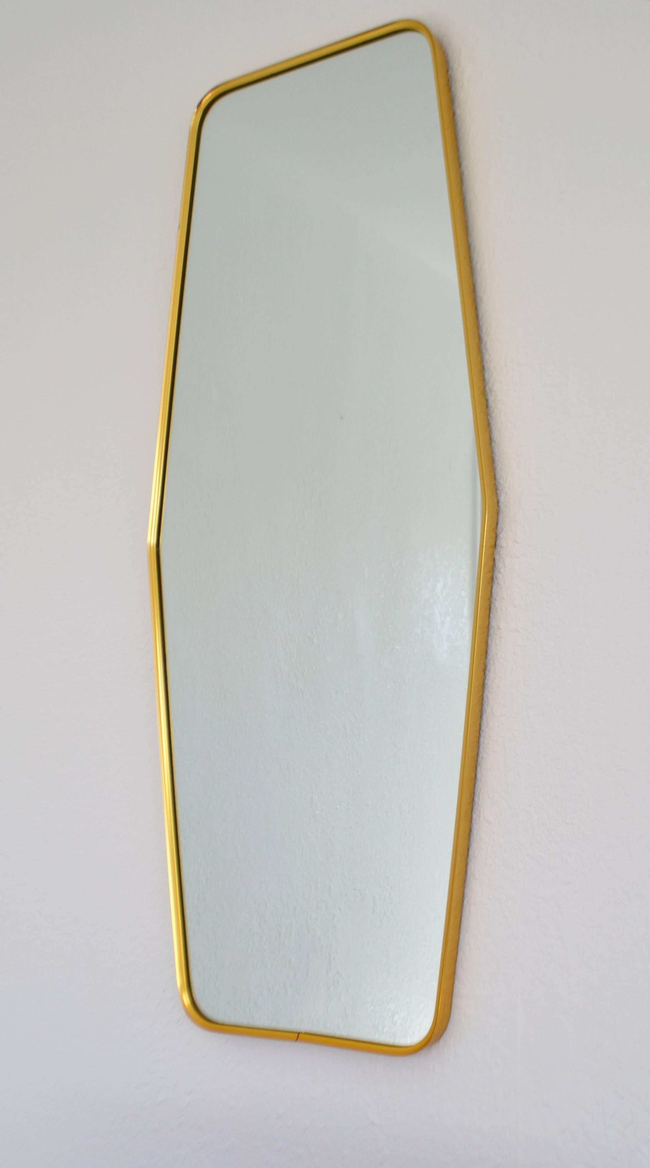 Glamorous midcentury brass wall mirror, circa 1960s. This striking art moderne inspired mirror is design with a sleek polished brass frame.