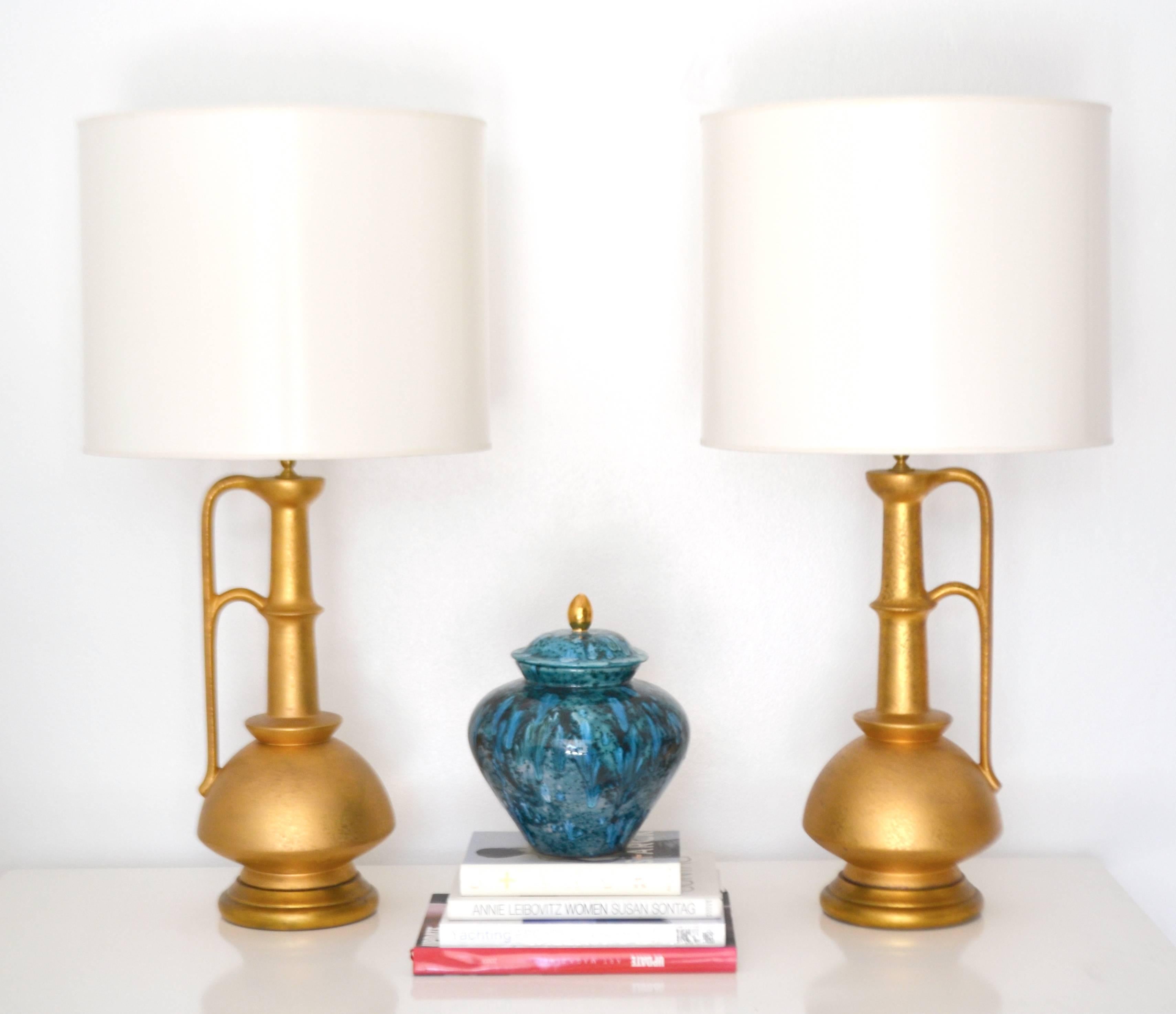 Striking pair of Italian midcentury ceramic jar form table lamps, circa 1950s-1960s. These glamorous highly decorative gilt glazed lamps are mounted on carved giltwood bases and wired with brass fittings and silk cords. Shades not