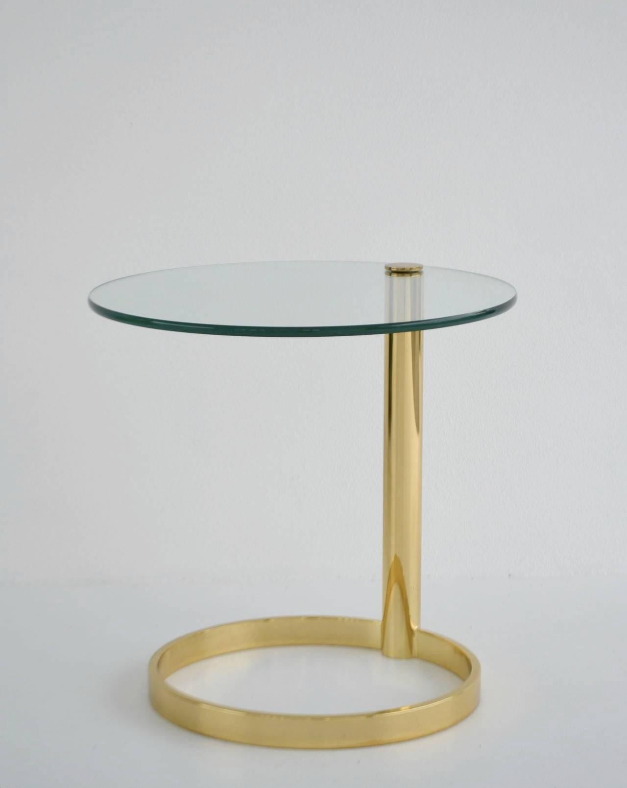 Stunning Postmodern polished brass round side table with glass top, circa 1970s-1980s by John Mascheroni. This sculptural architectural occasional table is designed with a brass column support and cantilevered swivel glass top.