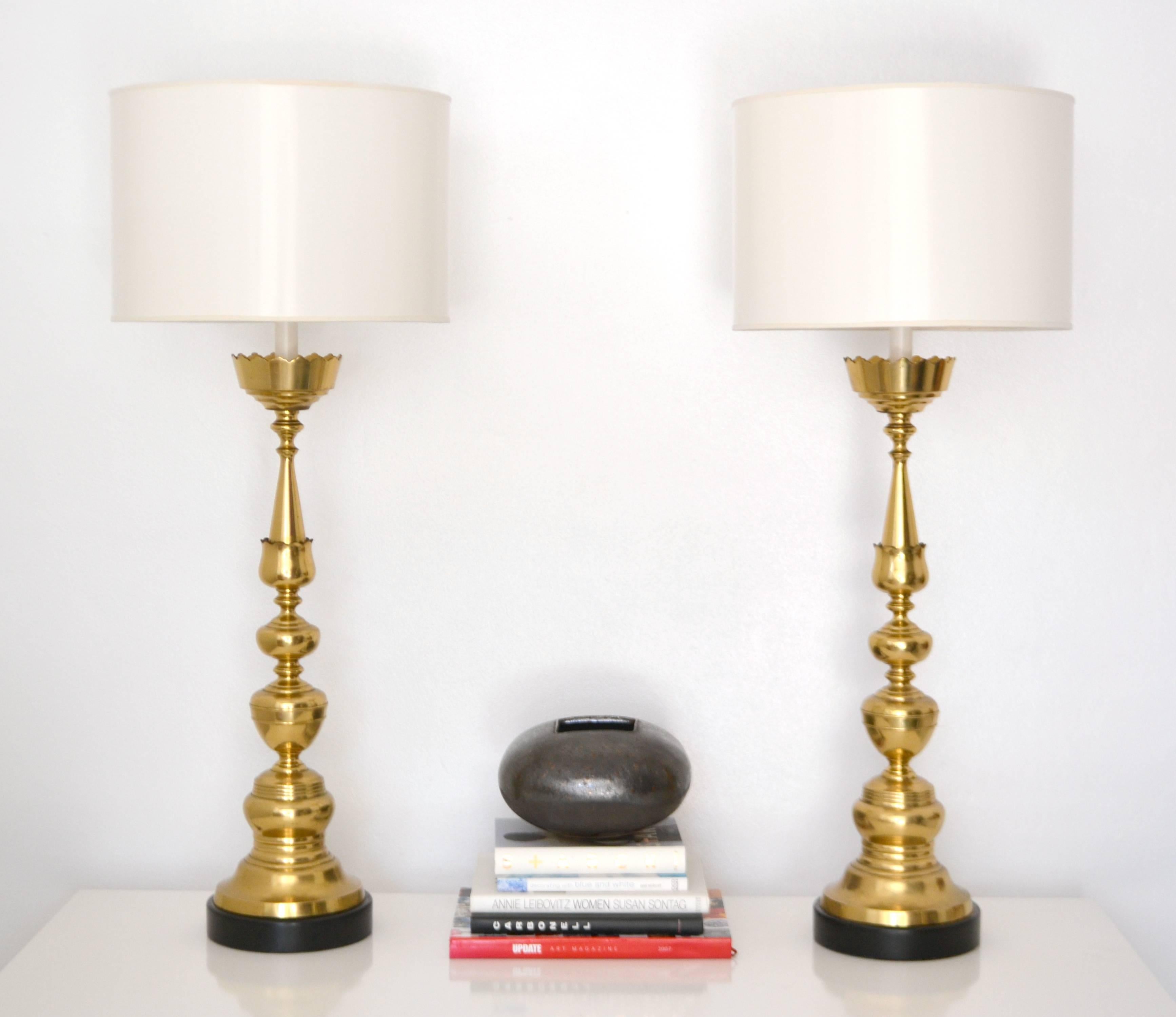 Glamorous pair of Italian Mid-Century turned brass candlestick table lamps, circa 1960s. These striking artisan crafted highly decorative lamps are mounted on turned wood ebonized bases and rewired with brass hardware and silk cords. Shades not