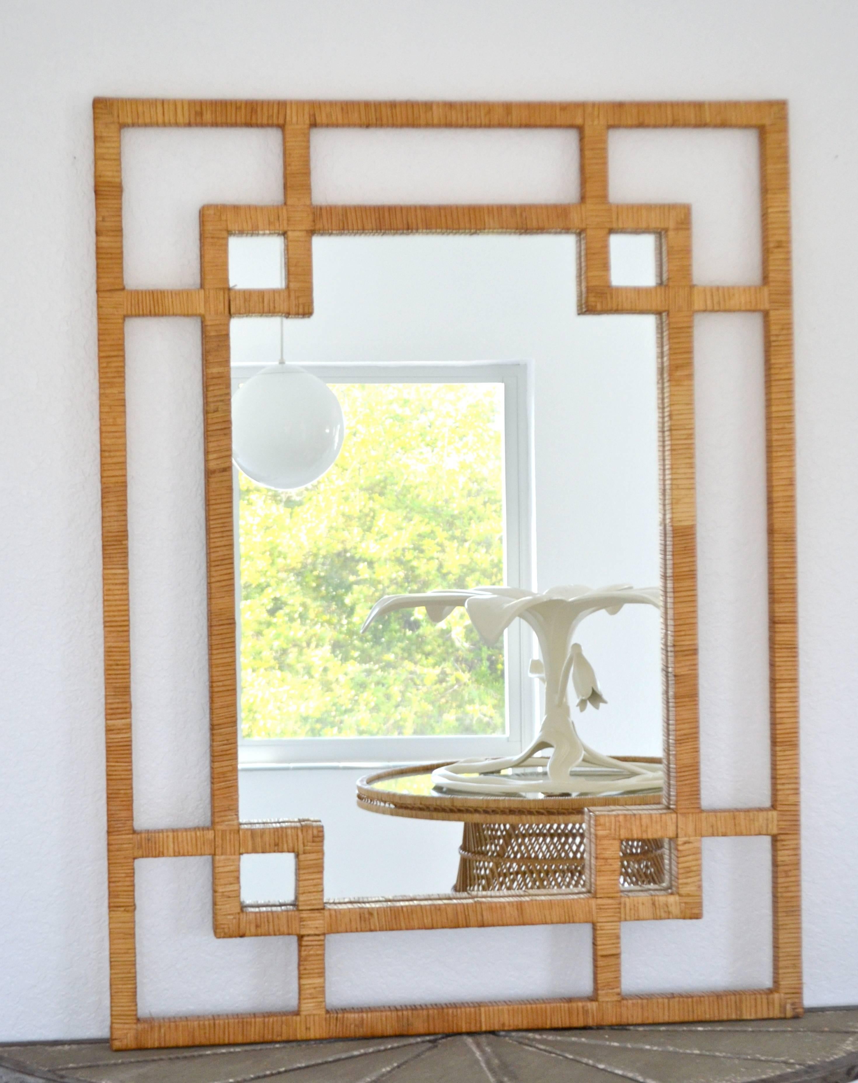 Striking midcentury rattan wall mirror, circa 1960s-1970s. This stunning artisan crafted rectangular mantel mirror is embellished with a highly decorative open fretwork surround. Measurements: The outer frame is 48